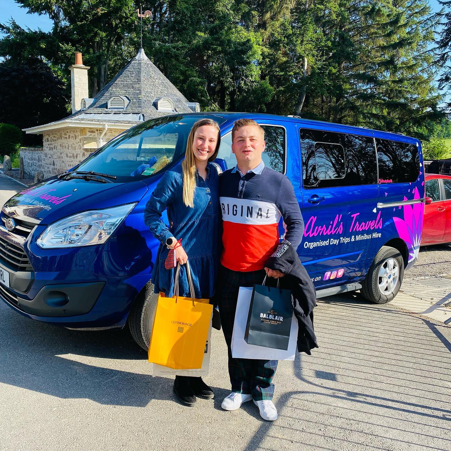 A man and a woman are standing in front of a blue van.