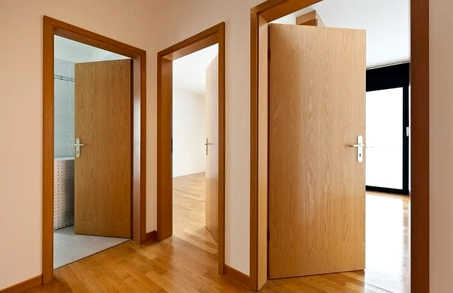 Porte di legno aperte in un corridoio luminoso con pavimenti in legno massello lucidato
