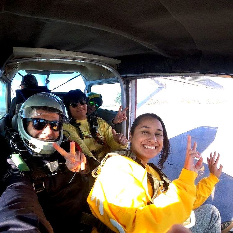 Skydiving students and instructors giving the peace sign in the Skydive Santa Cruz airplane as they take off. 