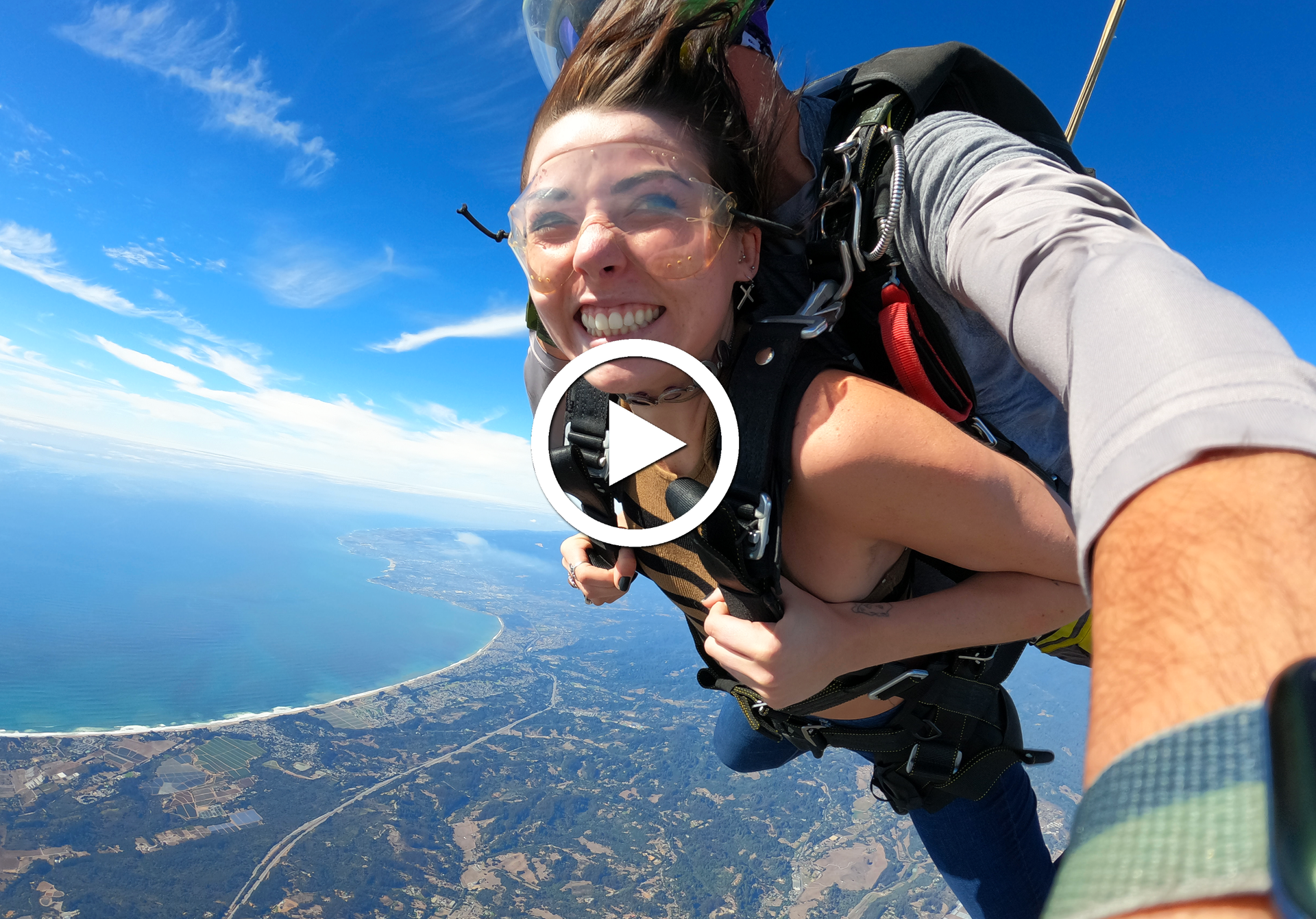 Skydive Santa Cruz female tandem student smiles during freefall with ocean in the background.