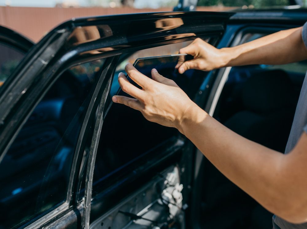 A Person is Installing a Window Tint on a Car — T&C Smash Repairs In Coffs Harbour, NSW