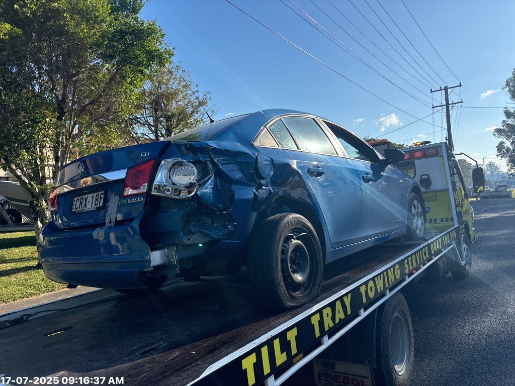 Blue Sedan Car Damaged on Tow Truck Cars in a Repair Shop — T&C Smash Repairs In Coffs Harbour, NSW