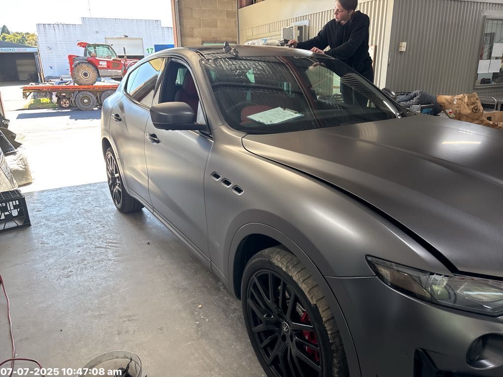 A Person Working on a Matte Gray Car in a Garage — T&C Smash Repairs In Coffs Harbour, NSW