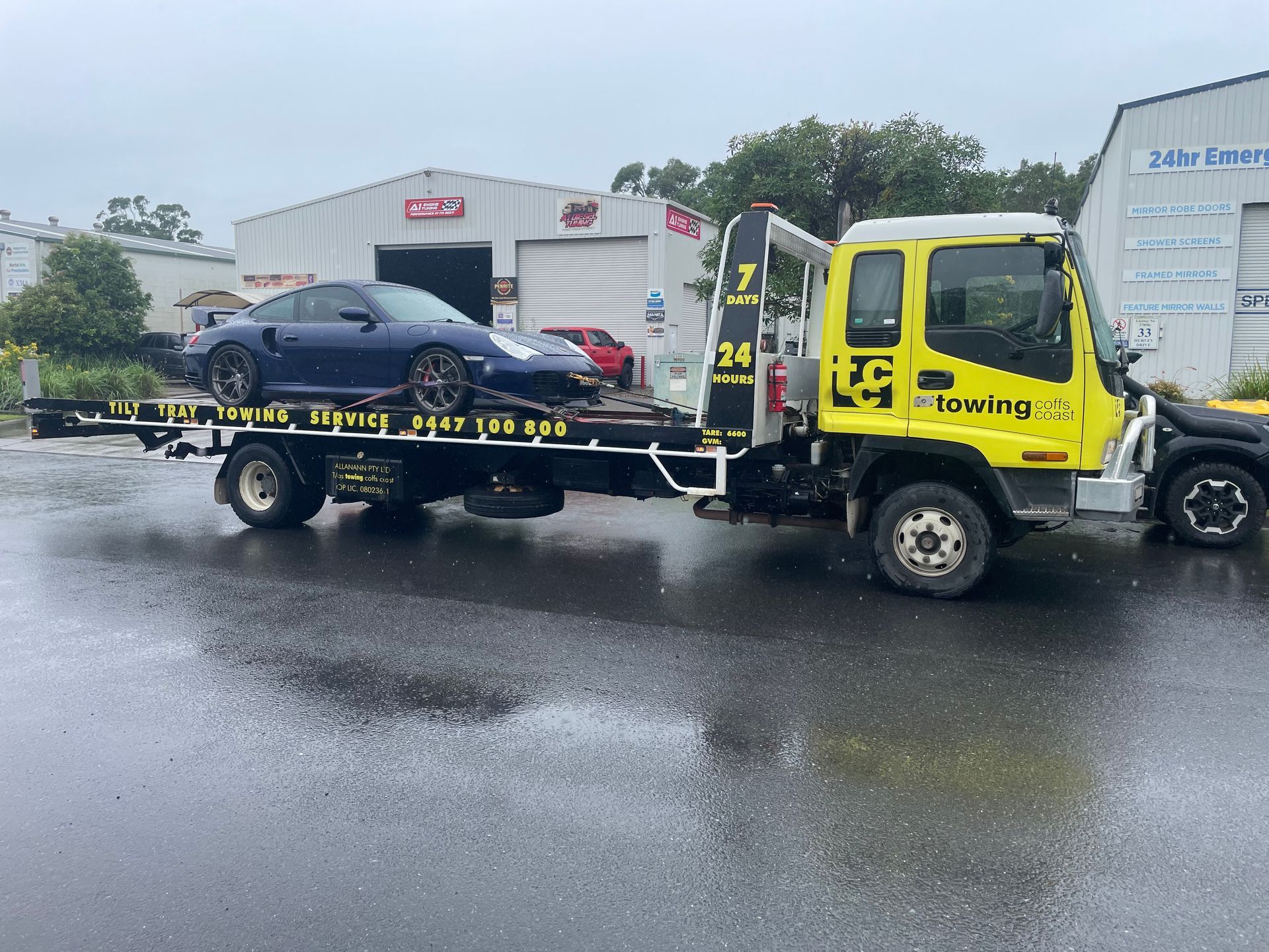 A Towing Truck With a Car on the Back of It — T&C Smash Repairs In Coffs Harbour, NSW