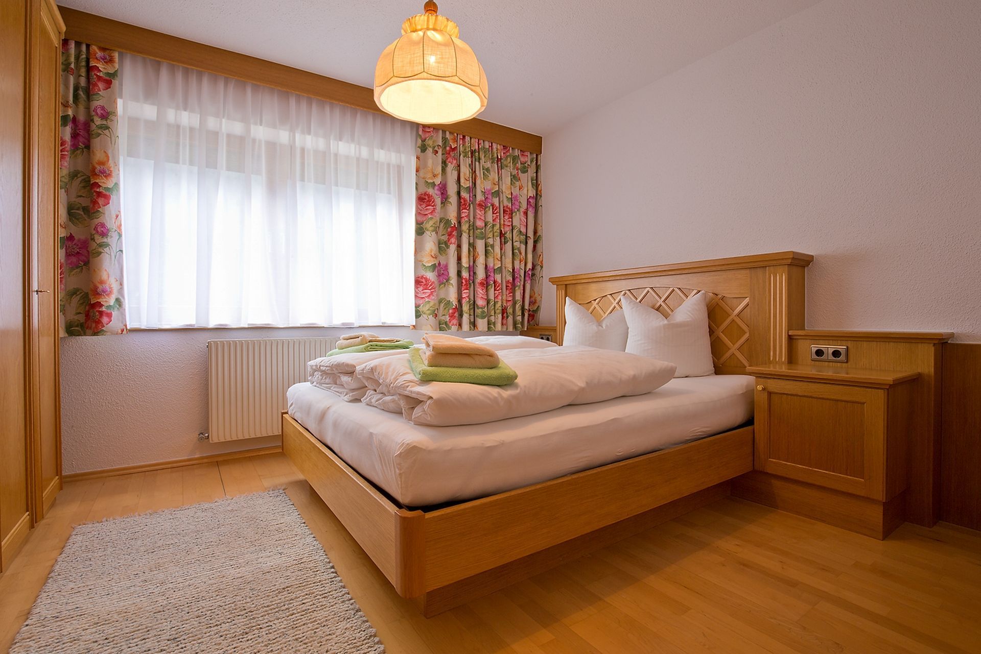 Ein Schlafzimmer mit großem Bett und geblümten Vorhängen