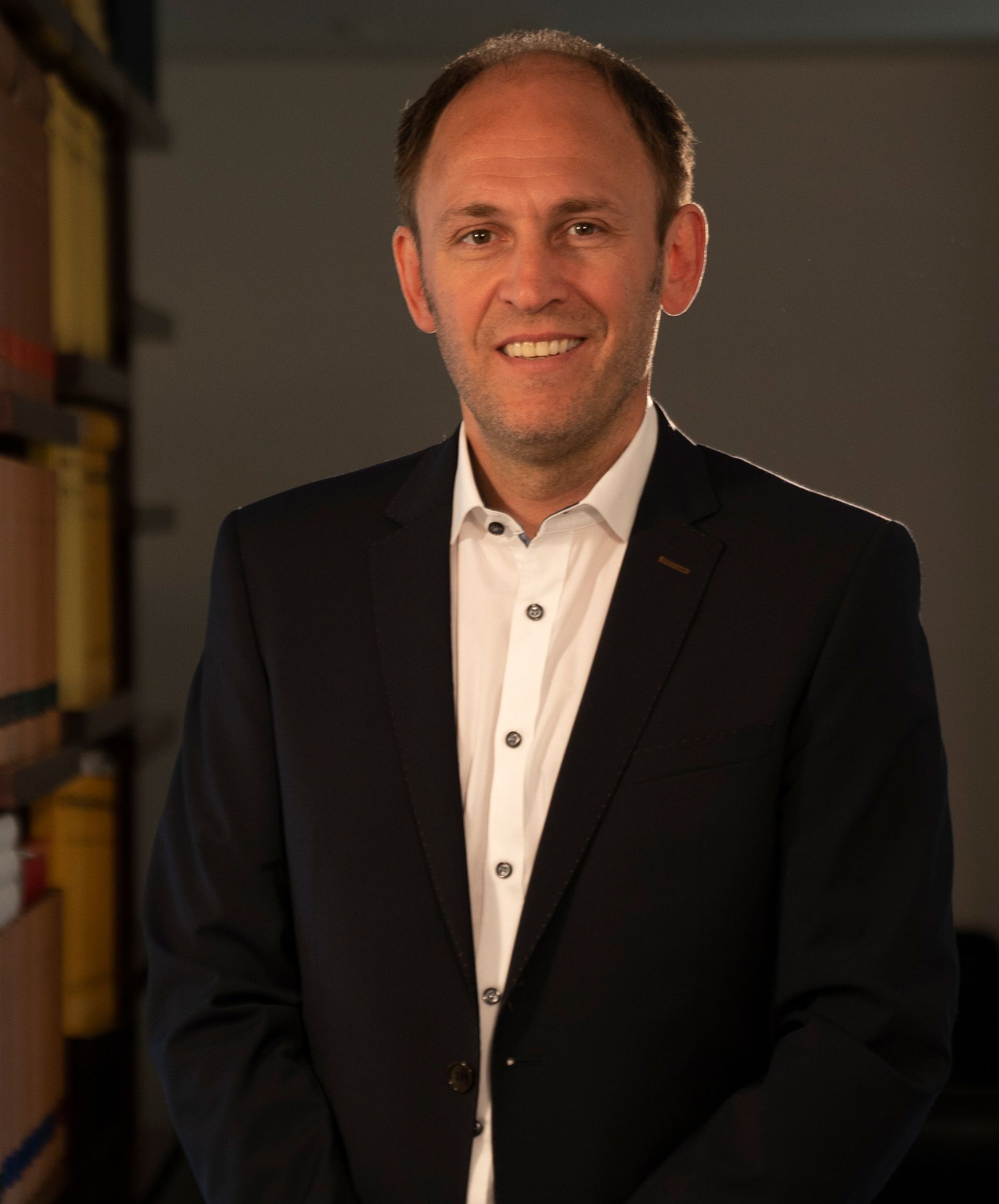 A man in a suit and white shirt is smiling for the camera