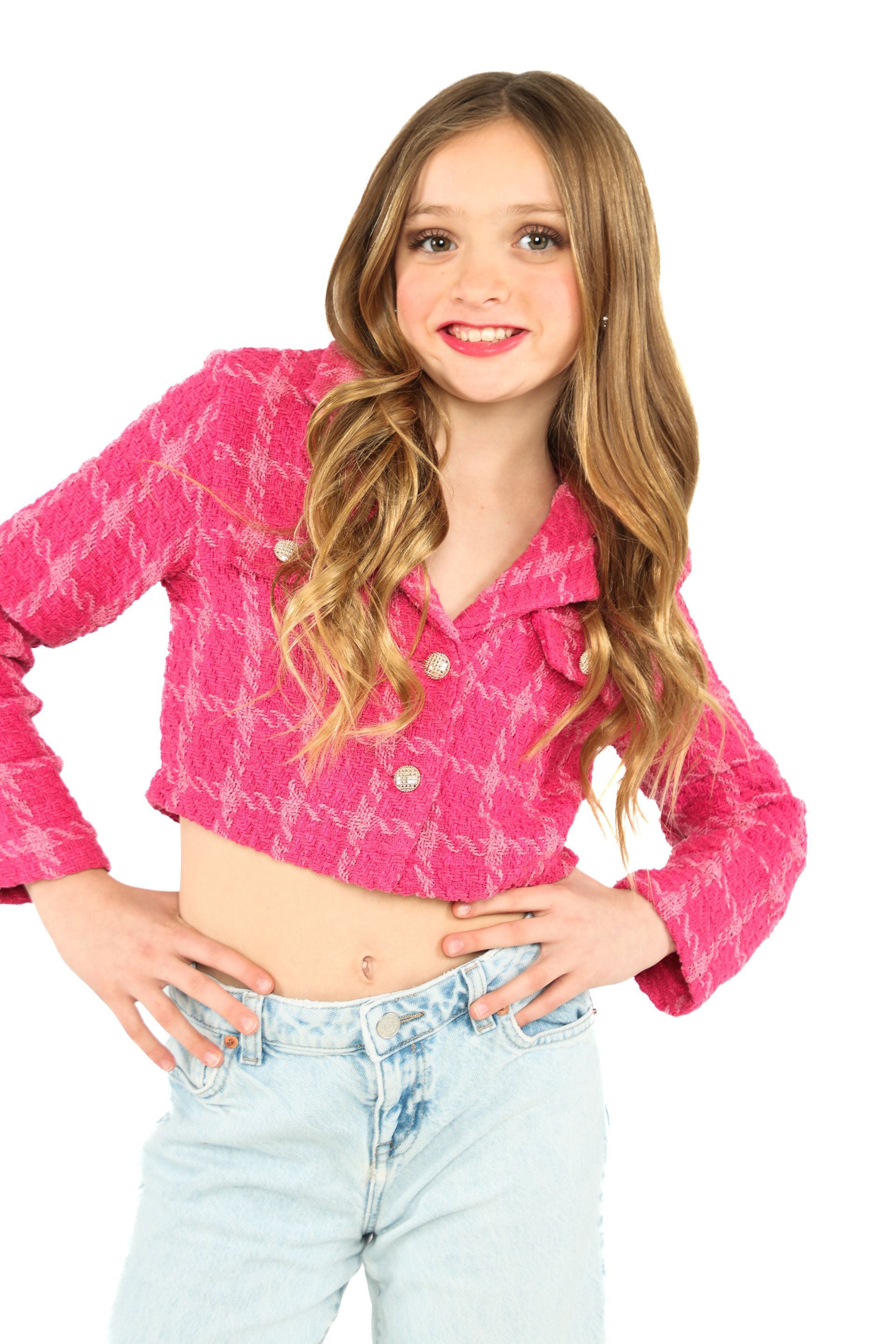 Person posing against a white background, wearing a bright pink top and light blue jeans, smiling.