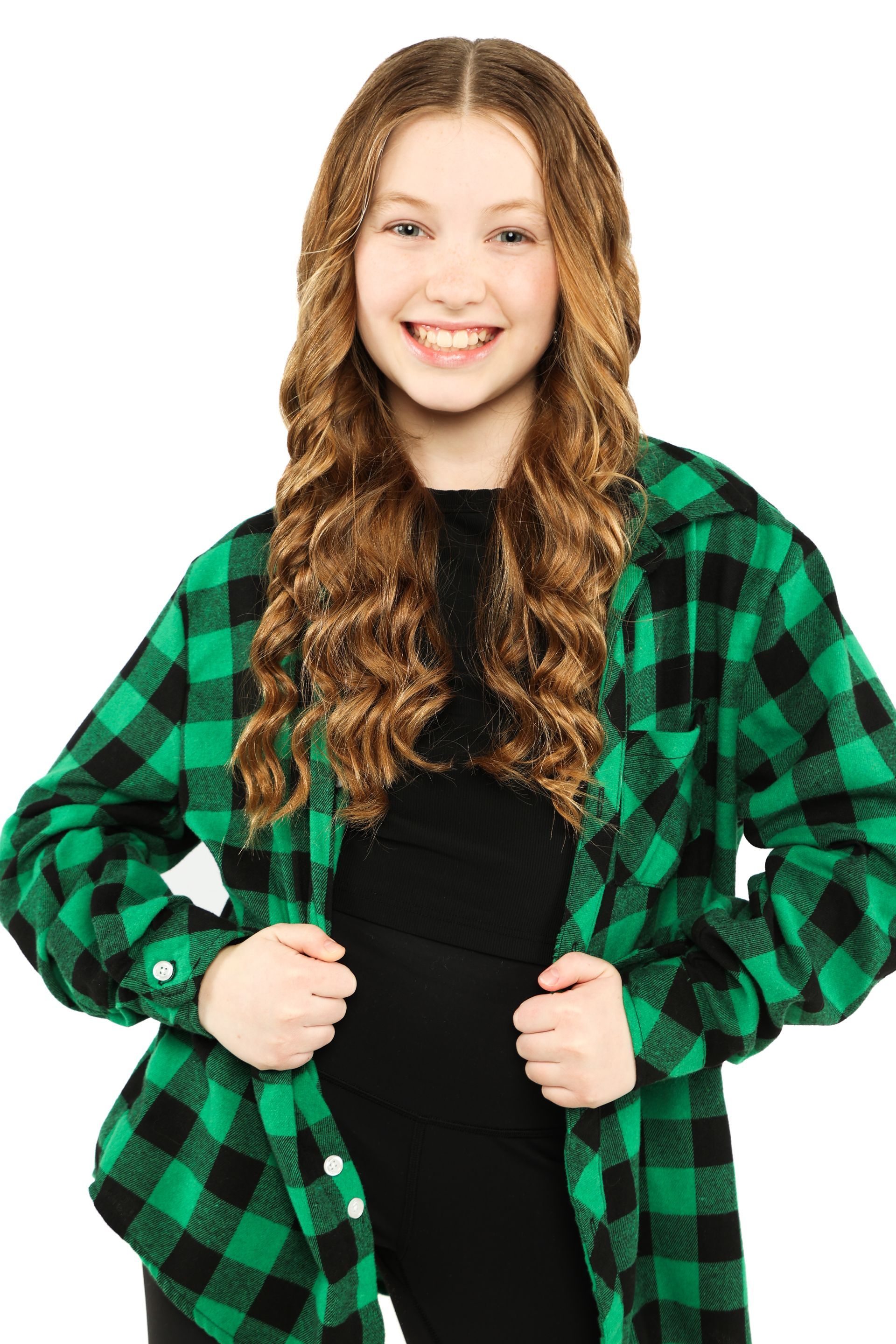Smiling person in a green-and-black plaid shirt over a black top, standing against a white background