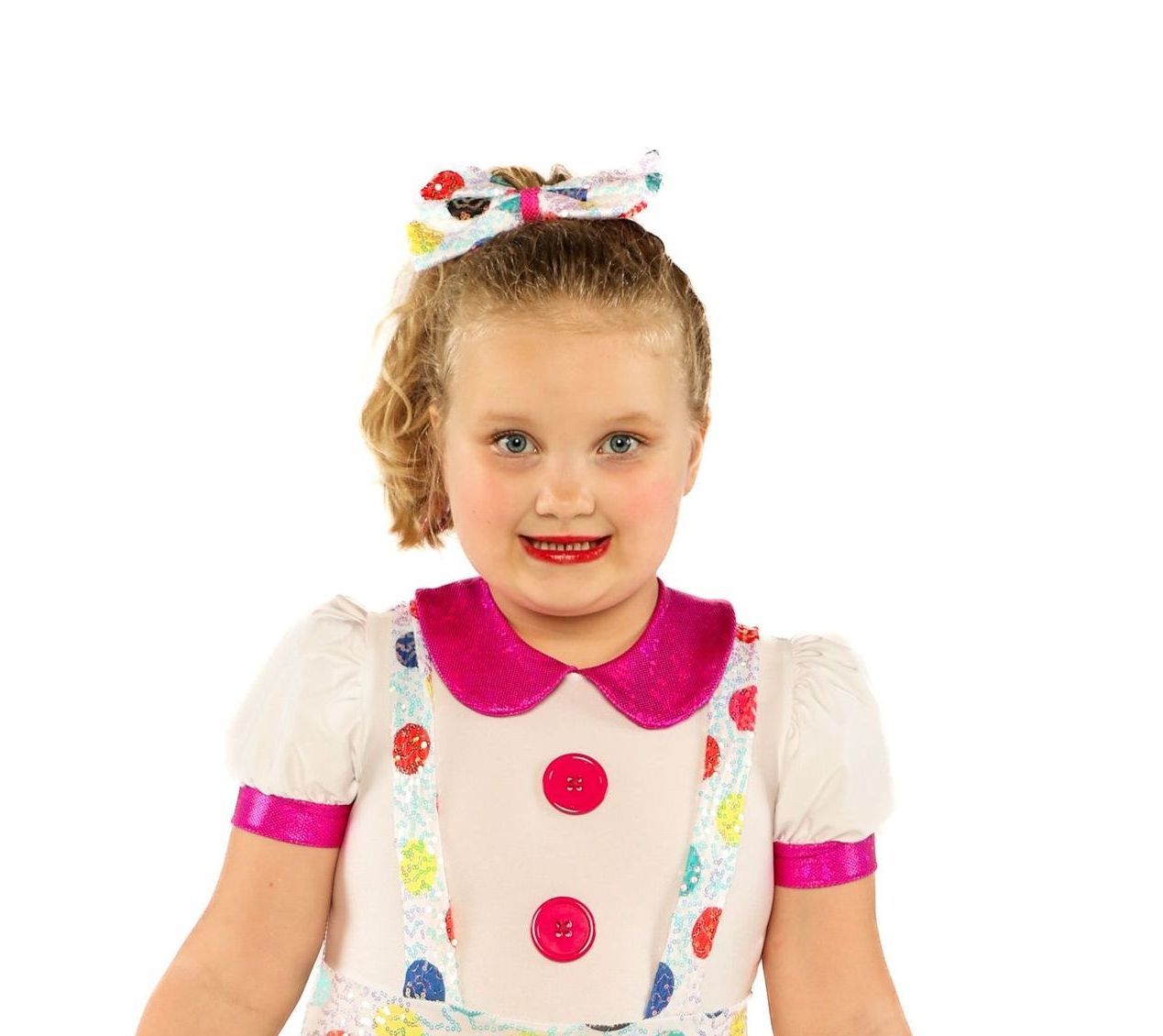 Smiling child in a white and pink clown costume with a polka-dot bow, against a white background