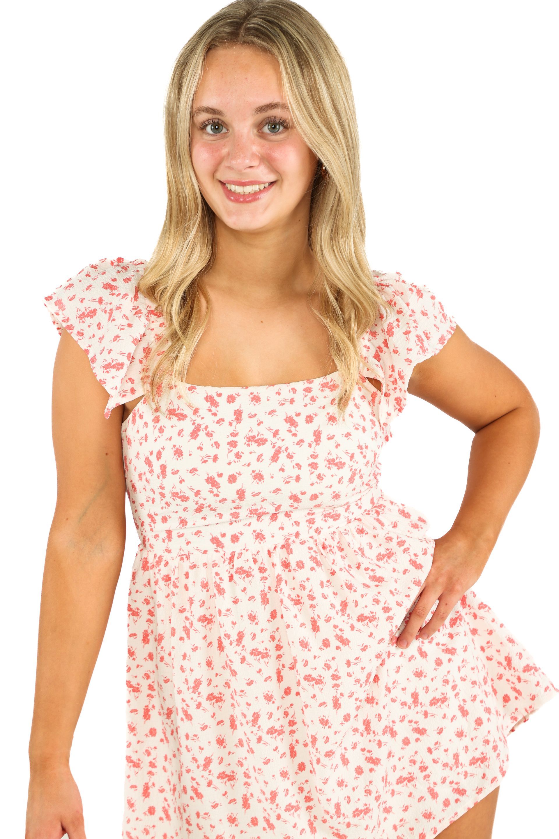 Smiling model in a pink floral dress with ruffled sleeves on a white background