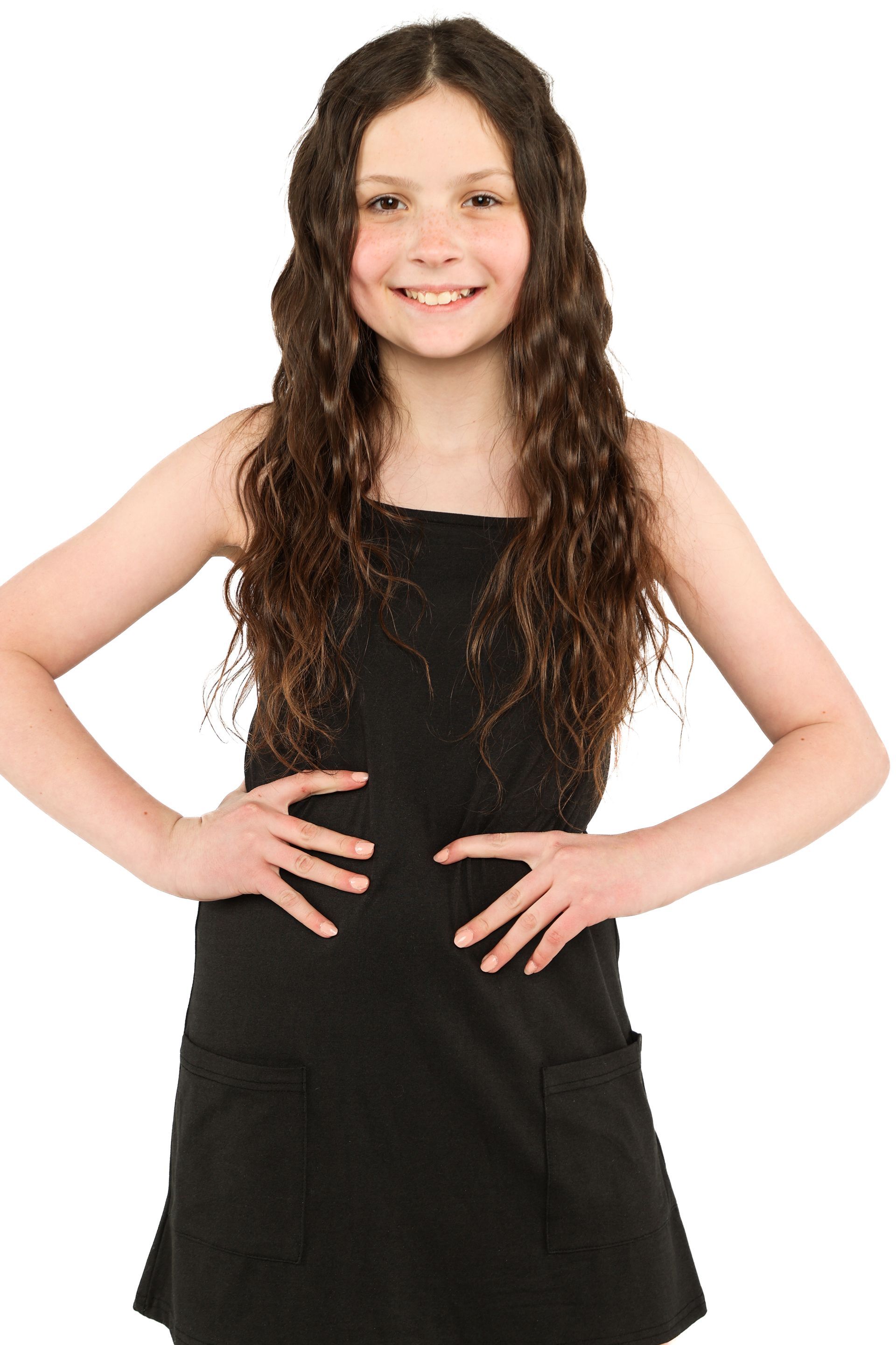 Person in a black dress standing with hands on hips and smiling against a white background