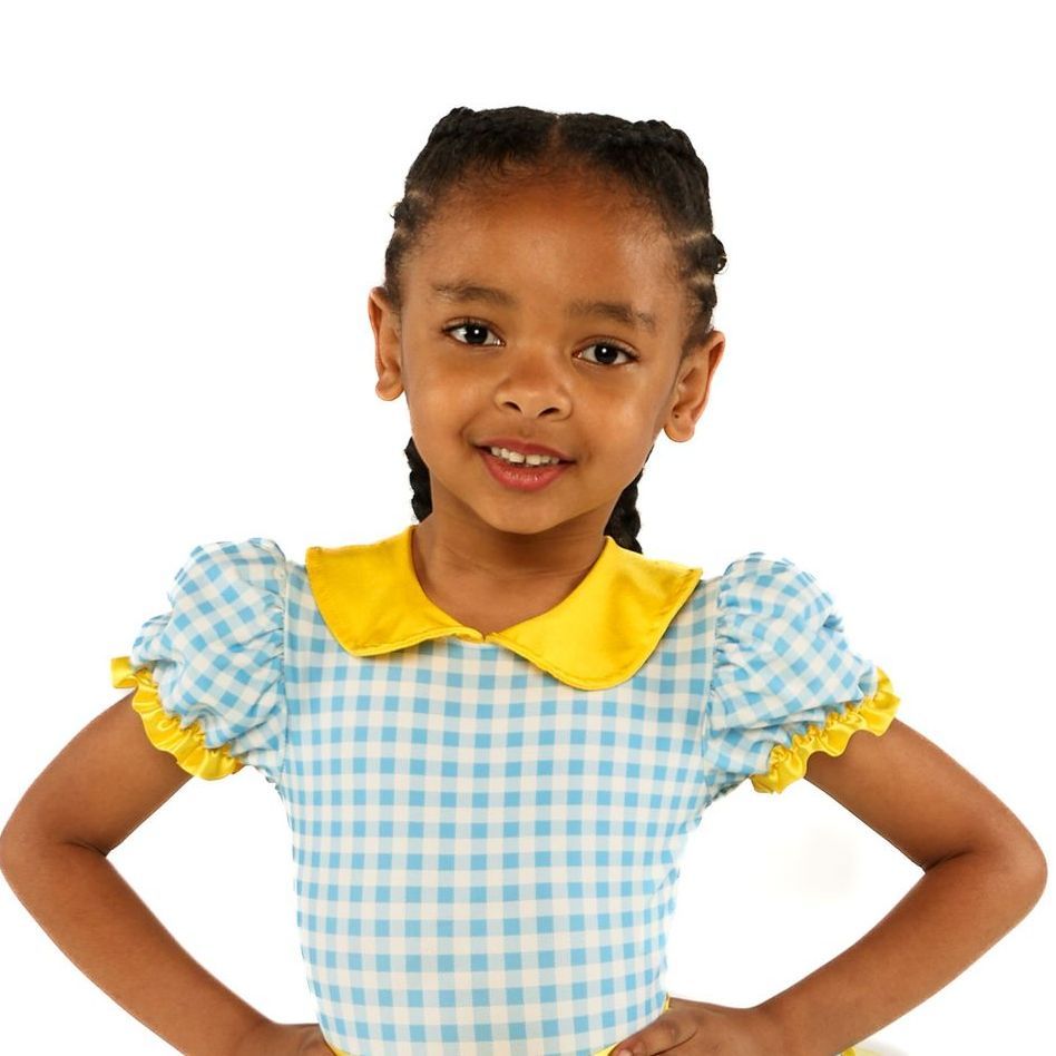 Smiling child in a blue gingham dress with a yellow collar, standing hands on hips against a white background