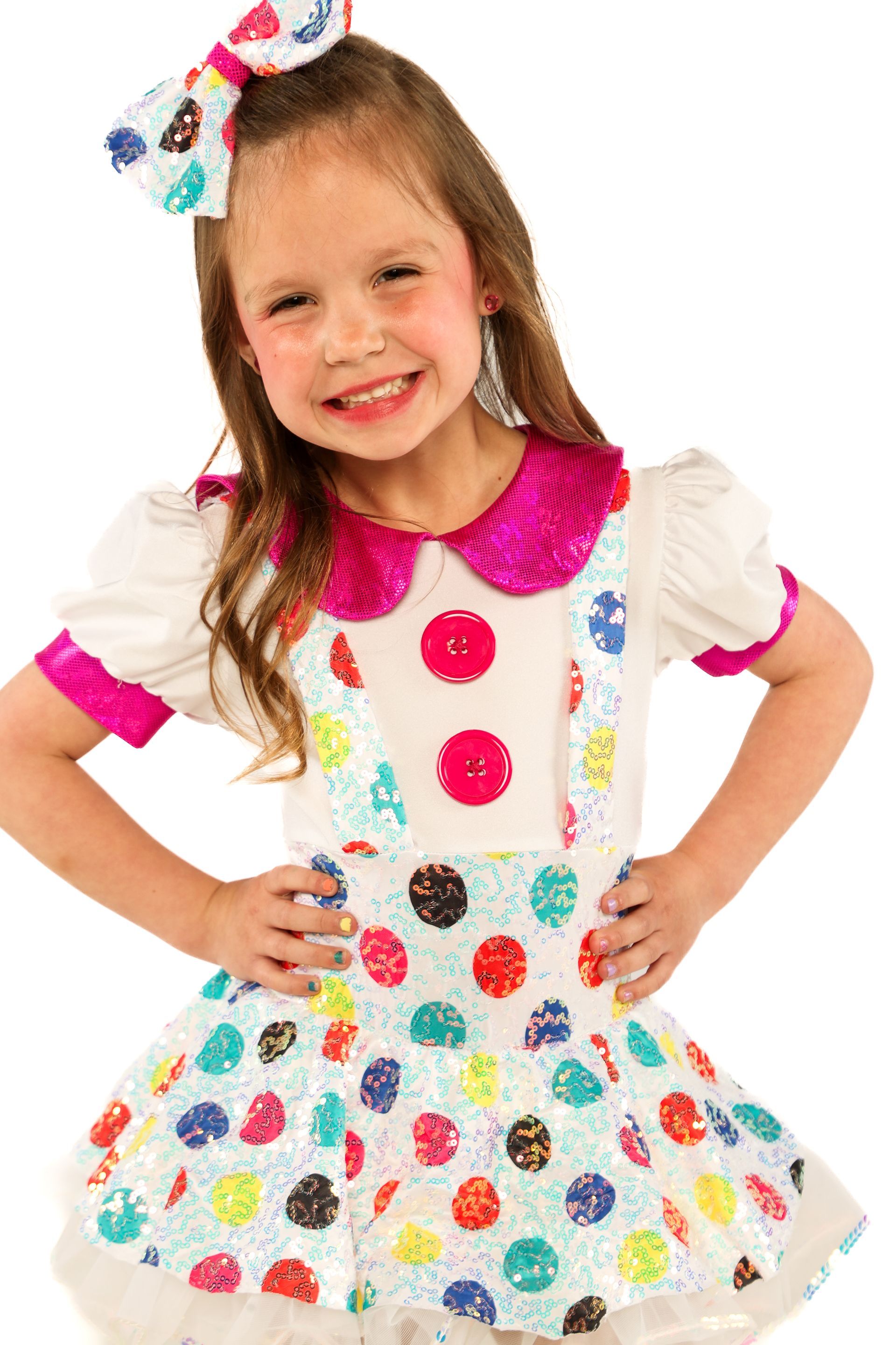 Smiling child in a white dress with colorful polka dots and a pink collar, hands on hips