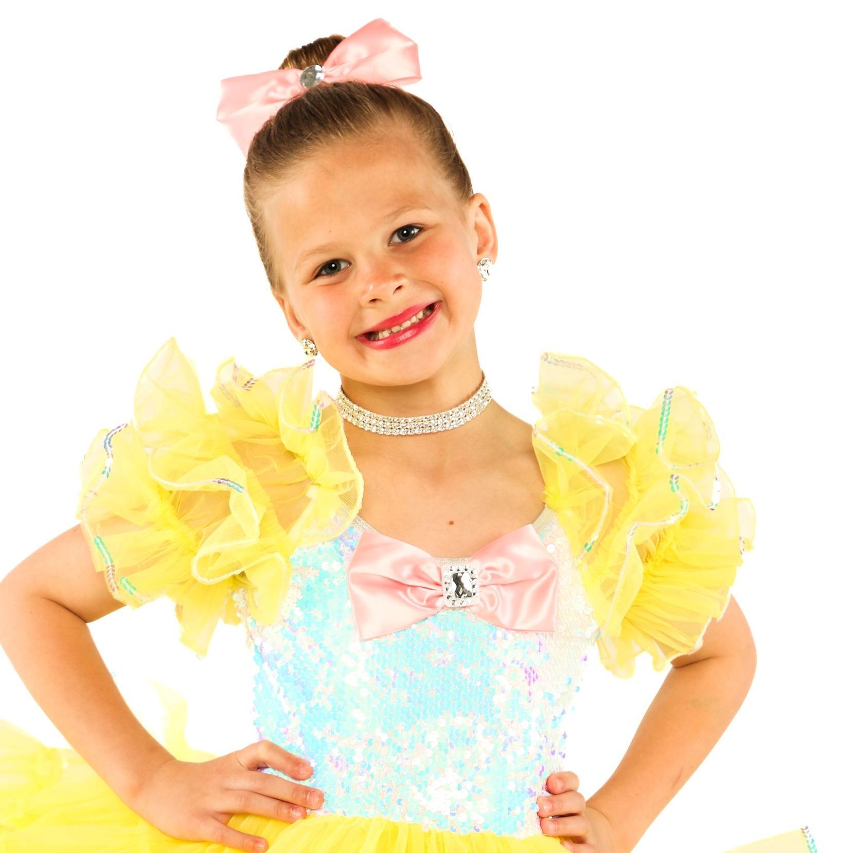 Smiling child in a pastel dress with yellow sleeves and a pink bow on a white background