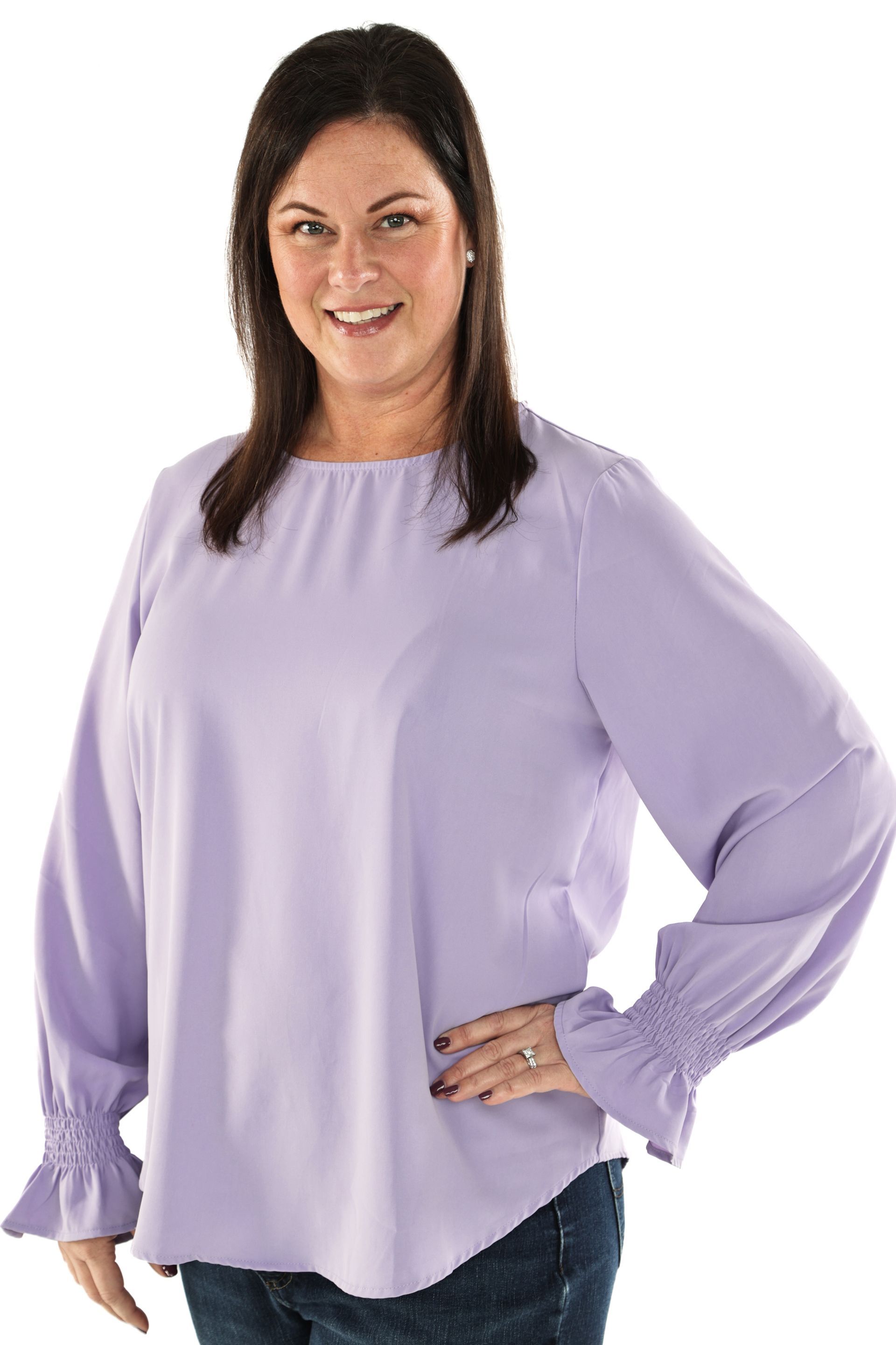Woman wearing a lavender blouse, standing with one hand on her hip against a white background