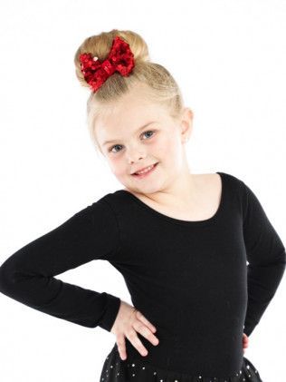 Portrait of a smiling child in a black top with a red bow in her hair, hand on hip