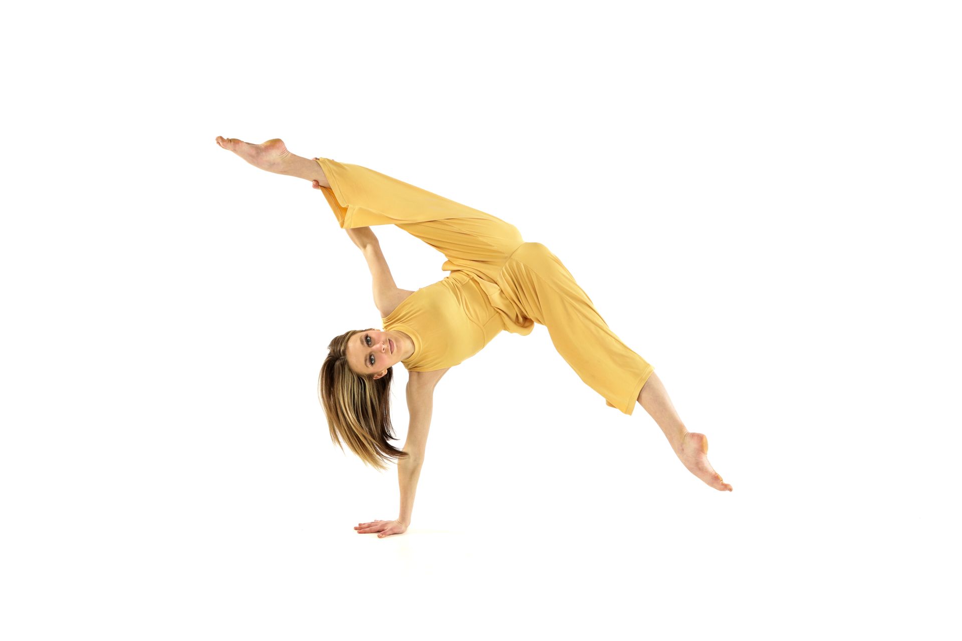 Person in a yellow outfit performing a one-handed acrobatic dance pose on a white background