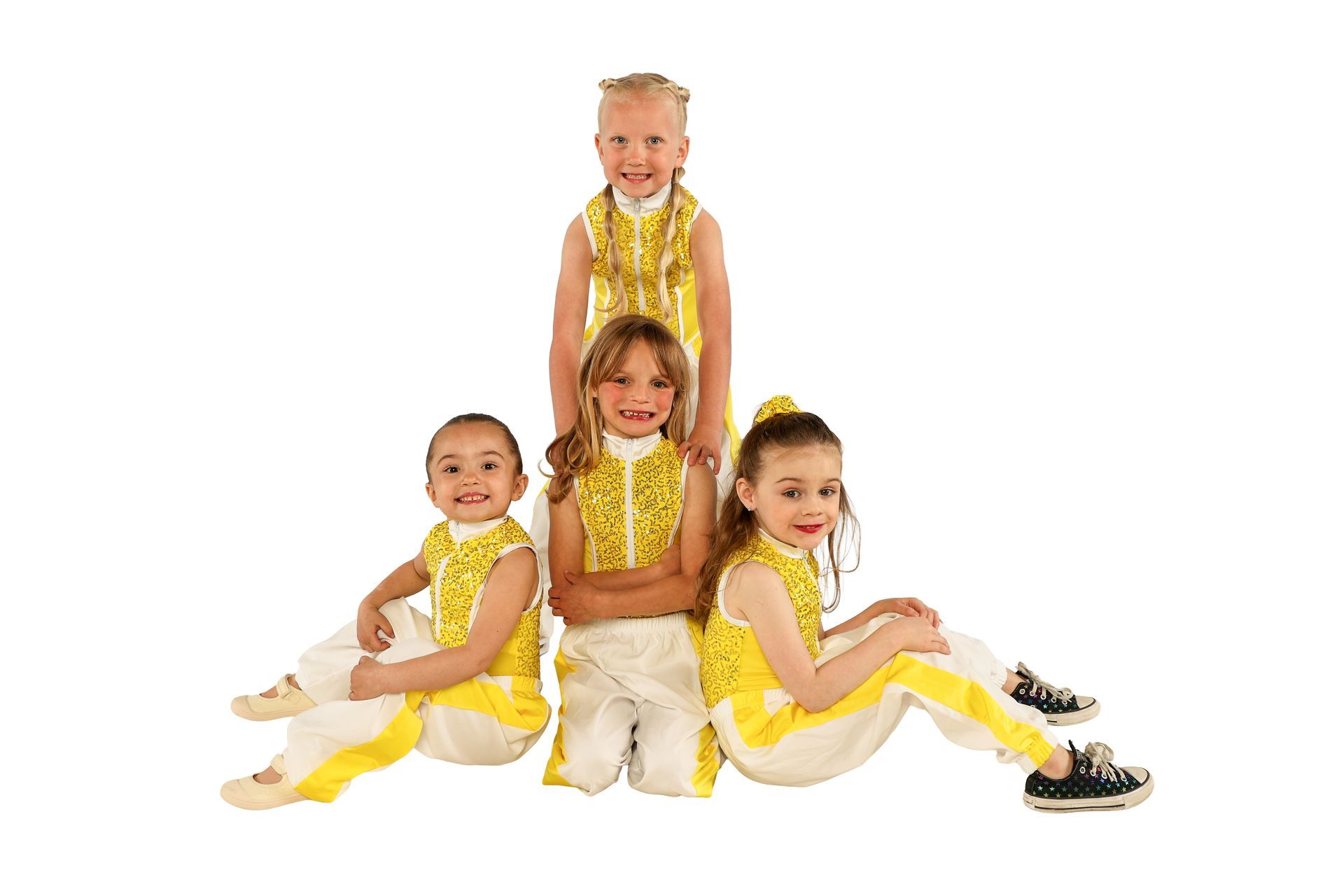 Four children in gold costumes posing against a white background, one seated in front and one standing behind.