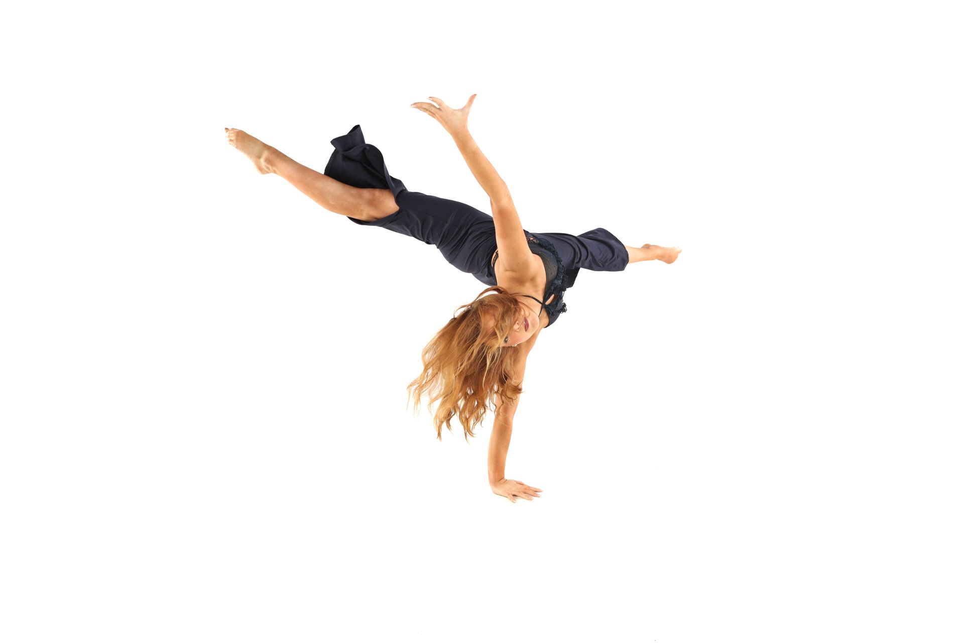 Dancer mid-air in a black outfit, performing a split leap on a white background