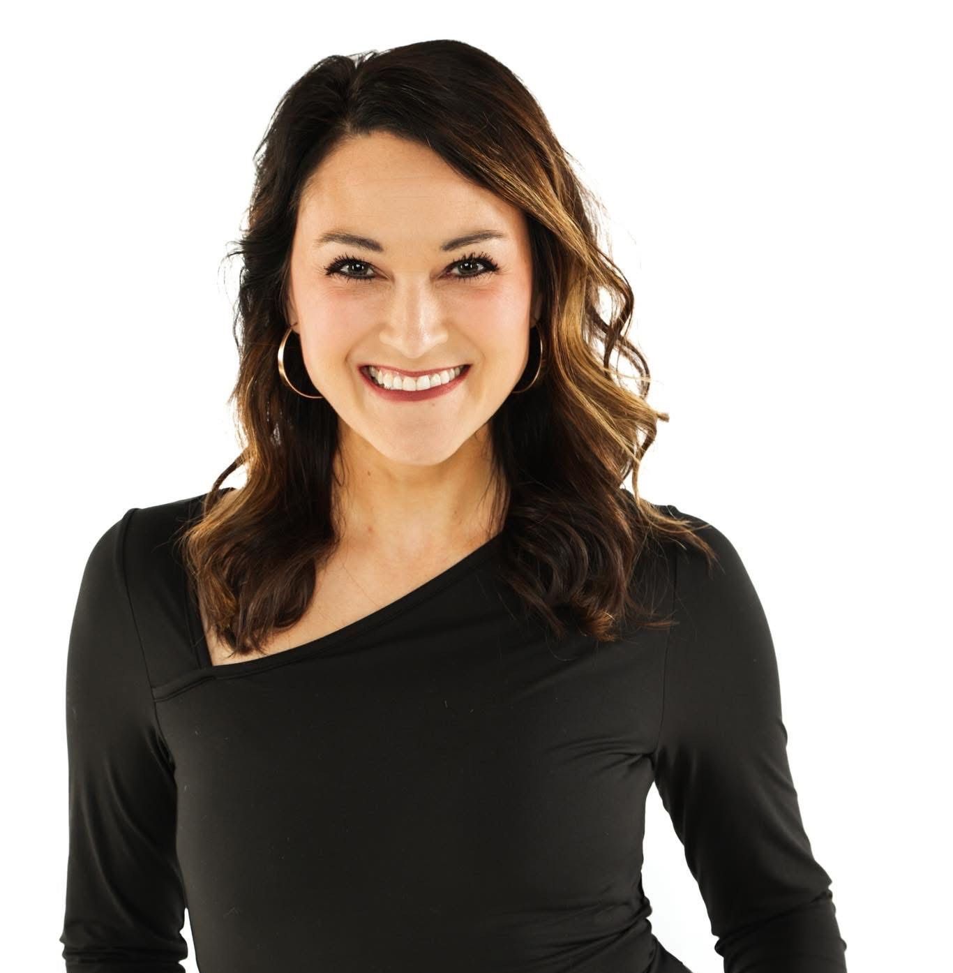 Smiling woman with shoulder-length dark hair in a black top against a white background
