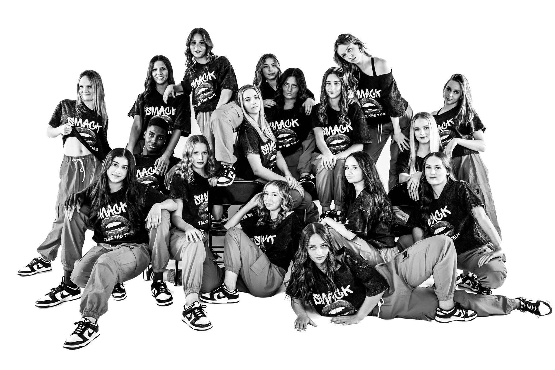 Large group posing together in matching black shirts against a plain white background.