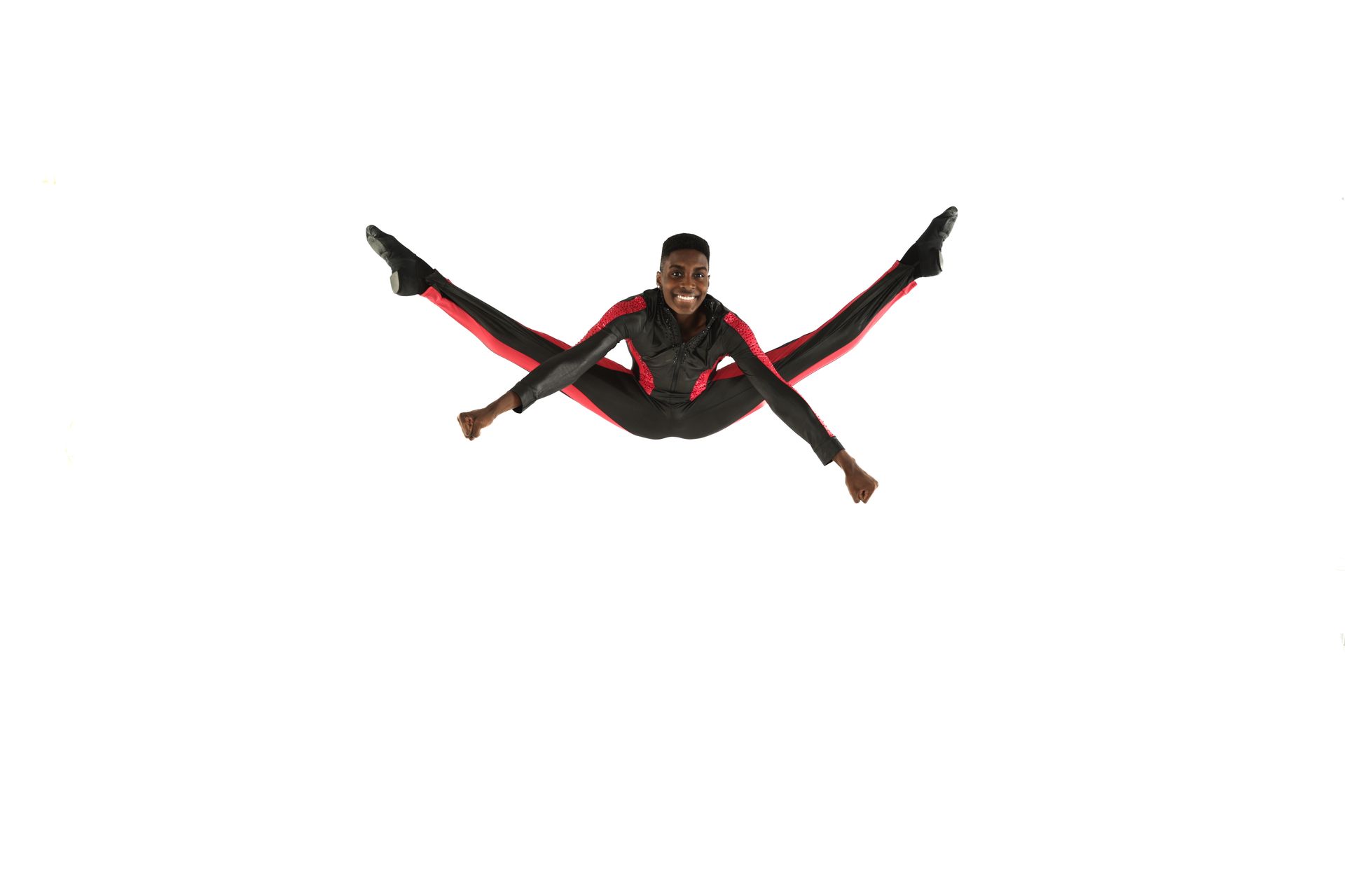 Athlete mid-air in a straddle jump, wearing a black and red outfit against a white background