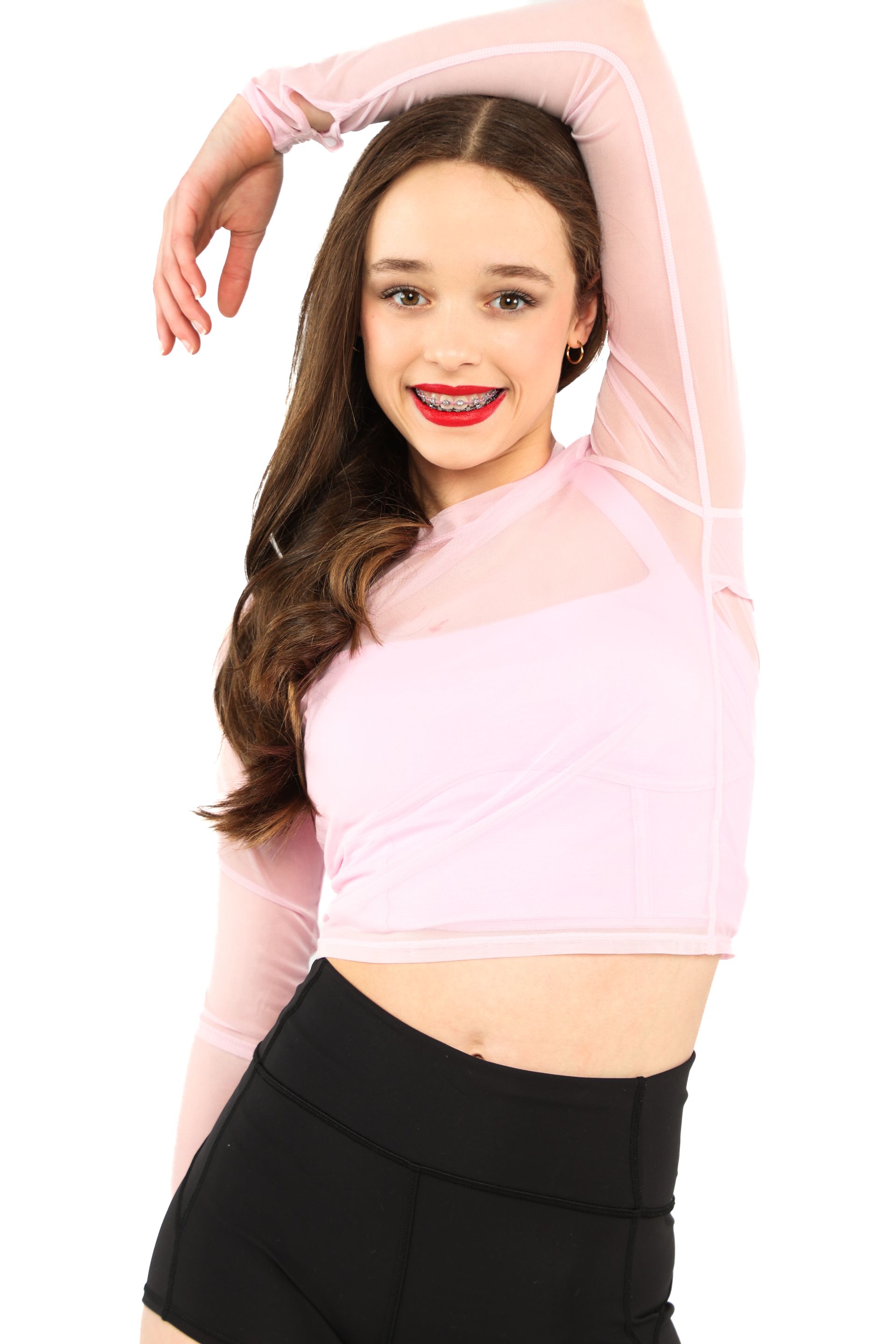 Woman in a pink top and black skirt posing with one arm raised against a white background