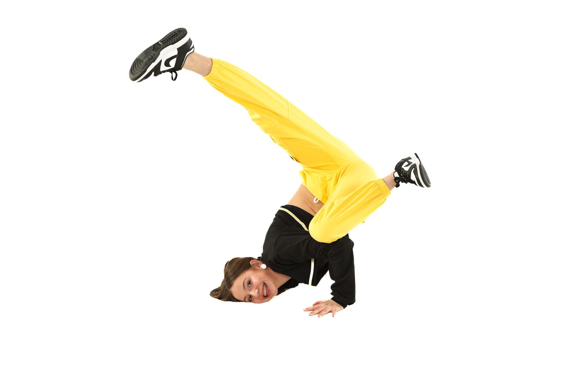 Person in yellow pants and black top doing a handstand on a white background