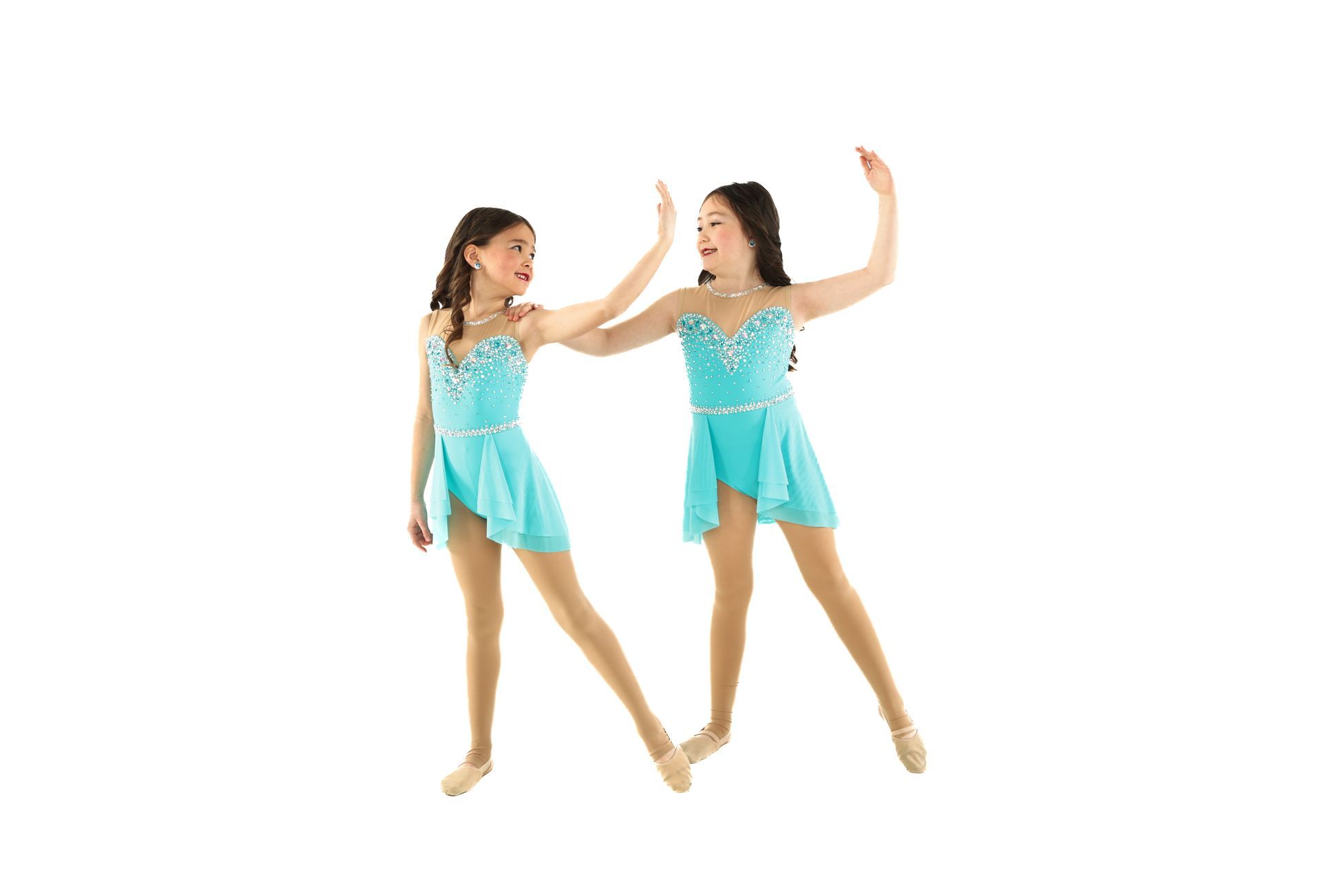 Two girls in turquoise dance costumes pose on a white background, one reaching toward the other.