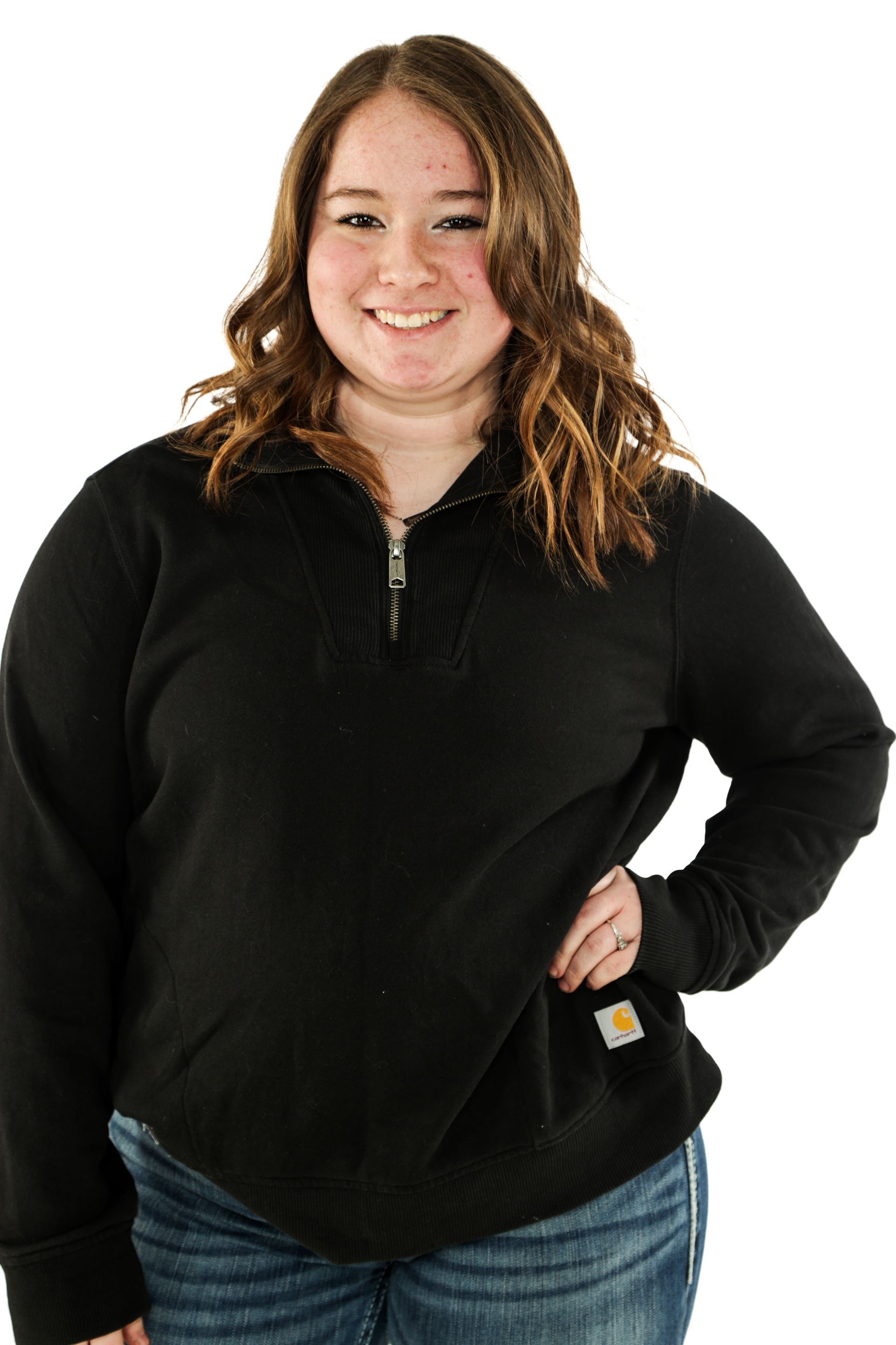 Smiling woman in a black top and jeans standing against a white background