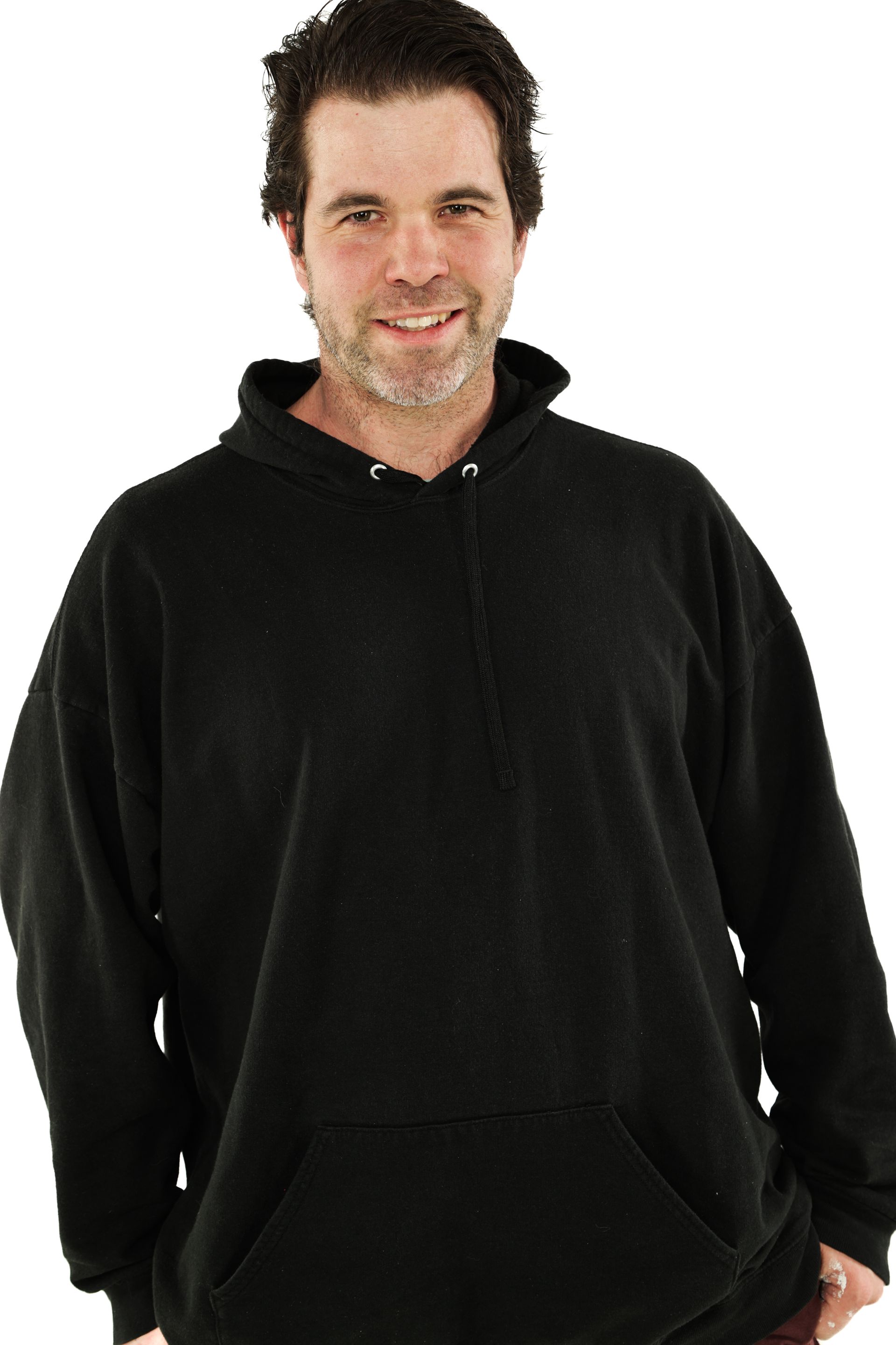 Man in a black hoodie standing against a white background, smiling at the camera