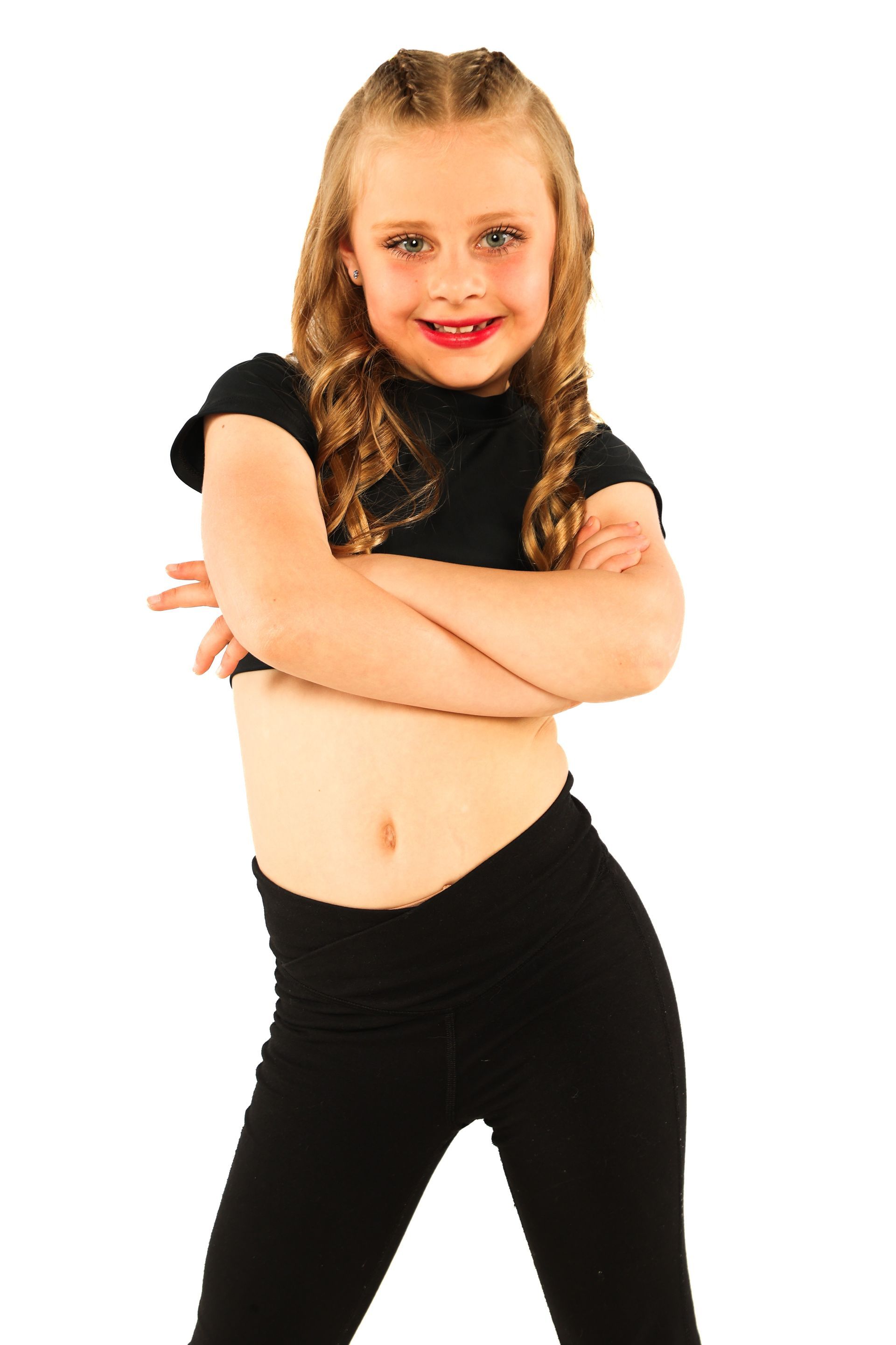 Person in black clothing with arms crossed, smiling against a white background