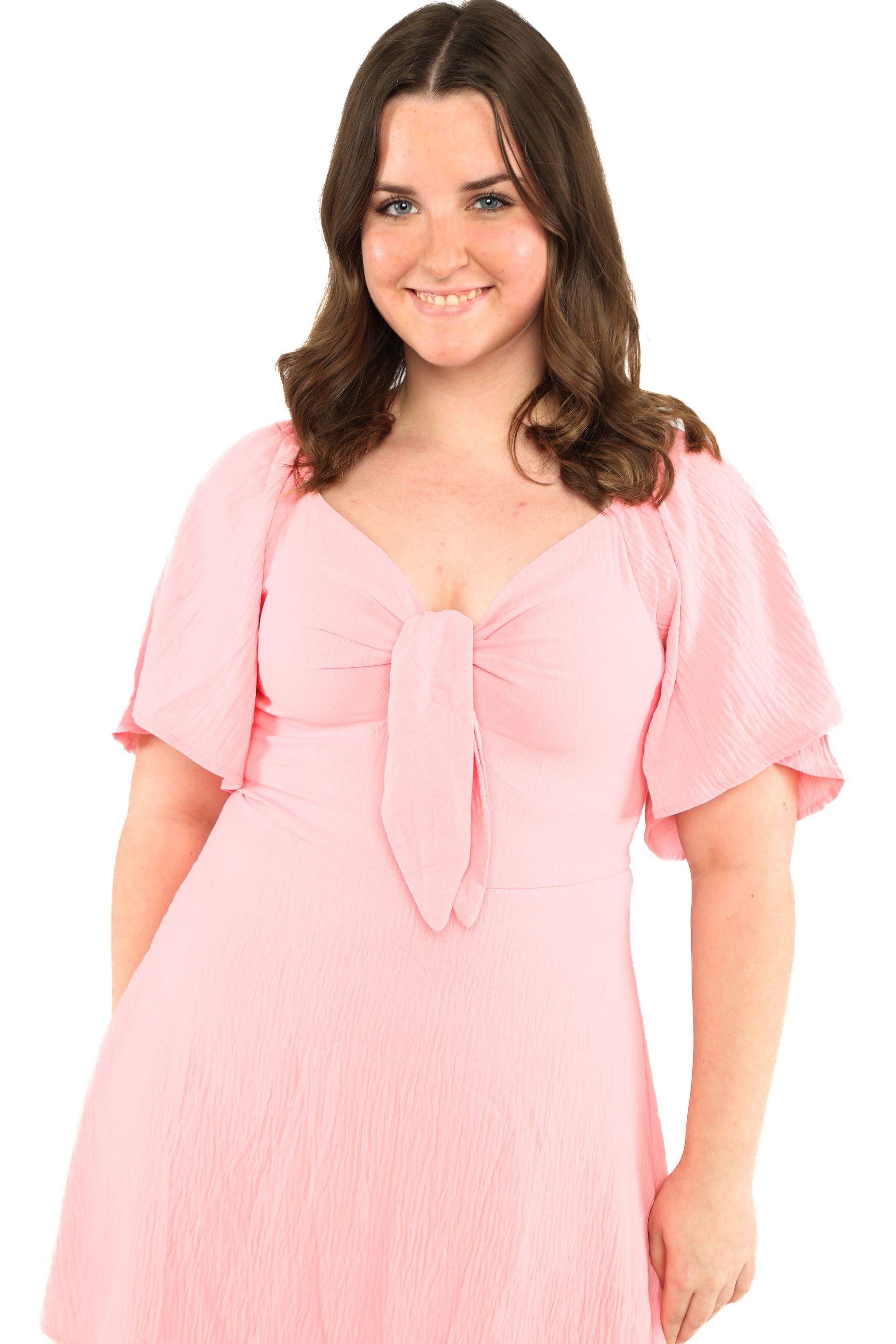 Woman in a light pink dress smiling against a white background