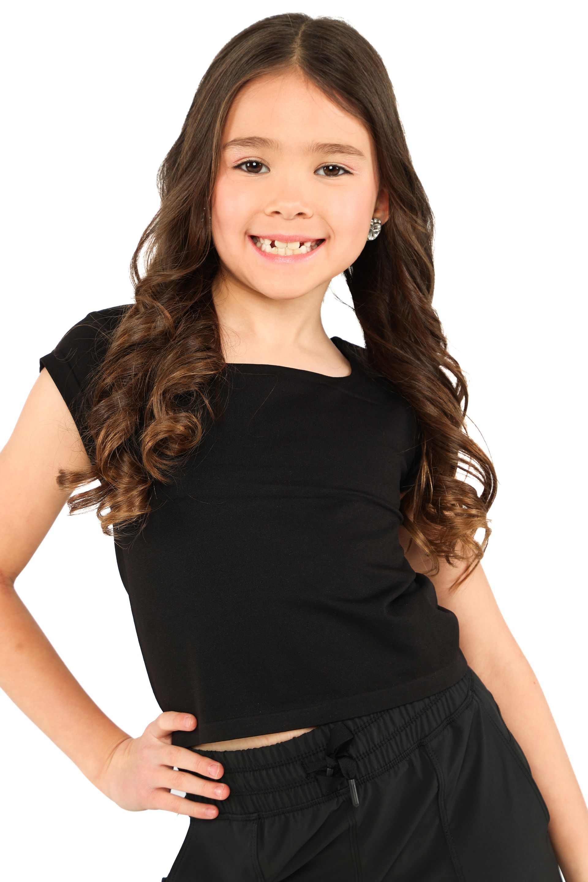 Smiling child in a black top and pants, posing against a white background