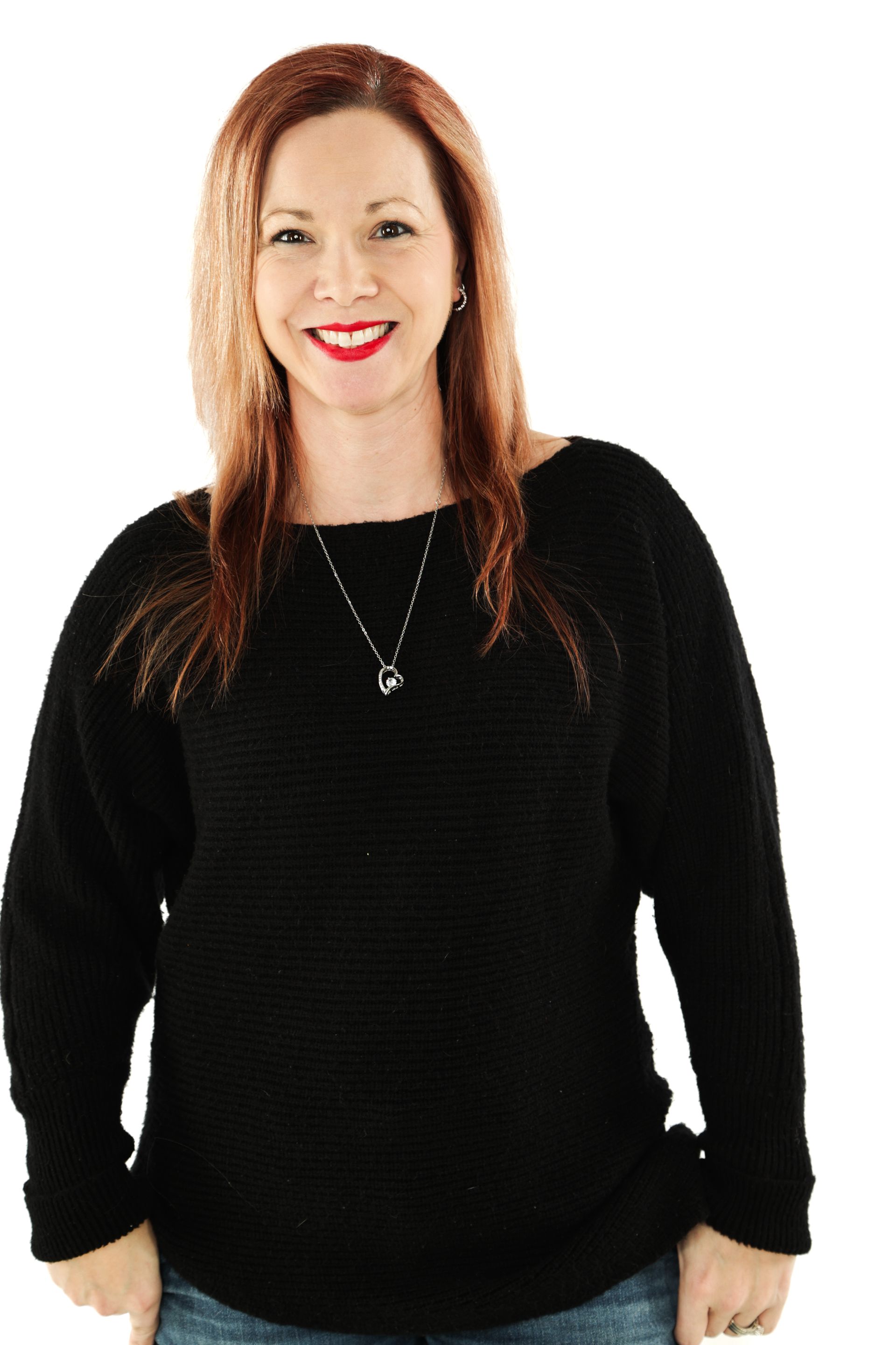 Woman in a black sweater smiling against a white background.