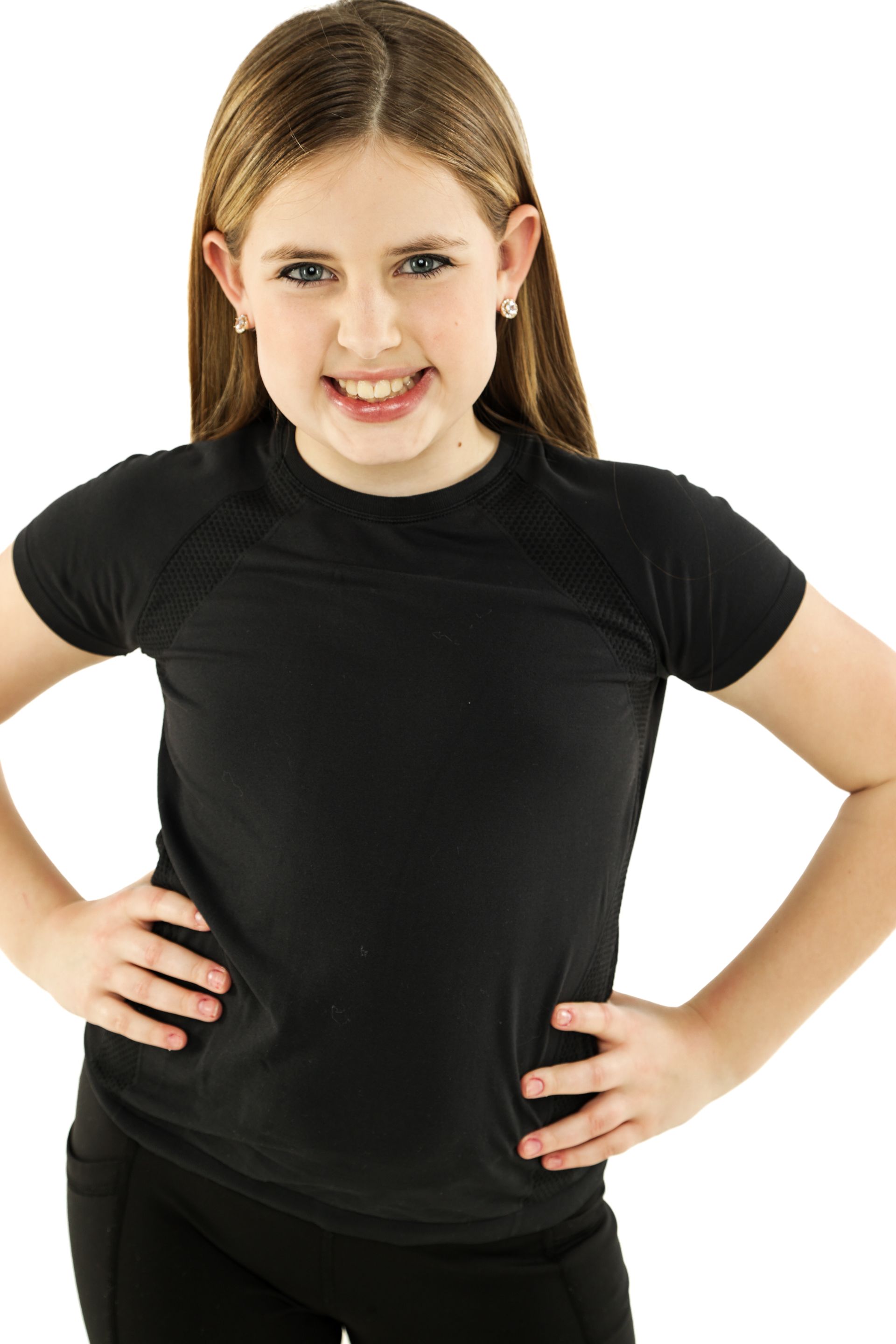 Smiling girl in a black T-shirt standing with hands on hips against a white background