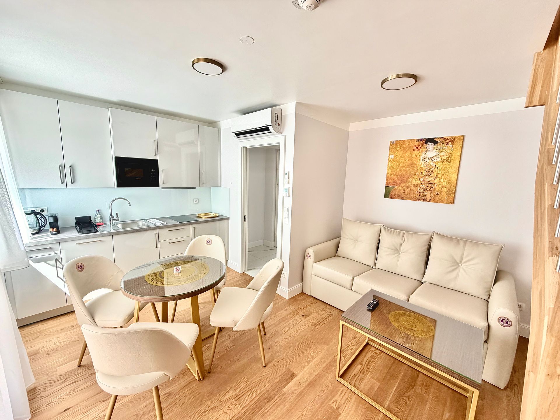 Bright modern living room with sofa, dining table, and open kitchen in soft neutral tones