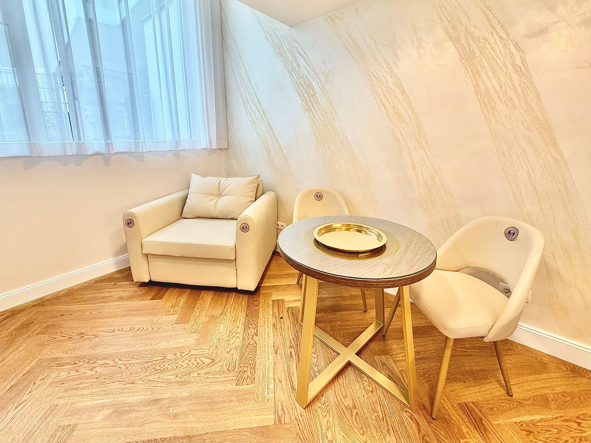 Cozy cream lounge with two chairs and a round wooden table on a light wood floor