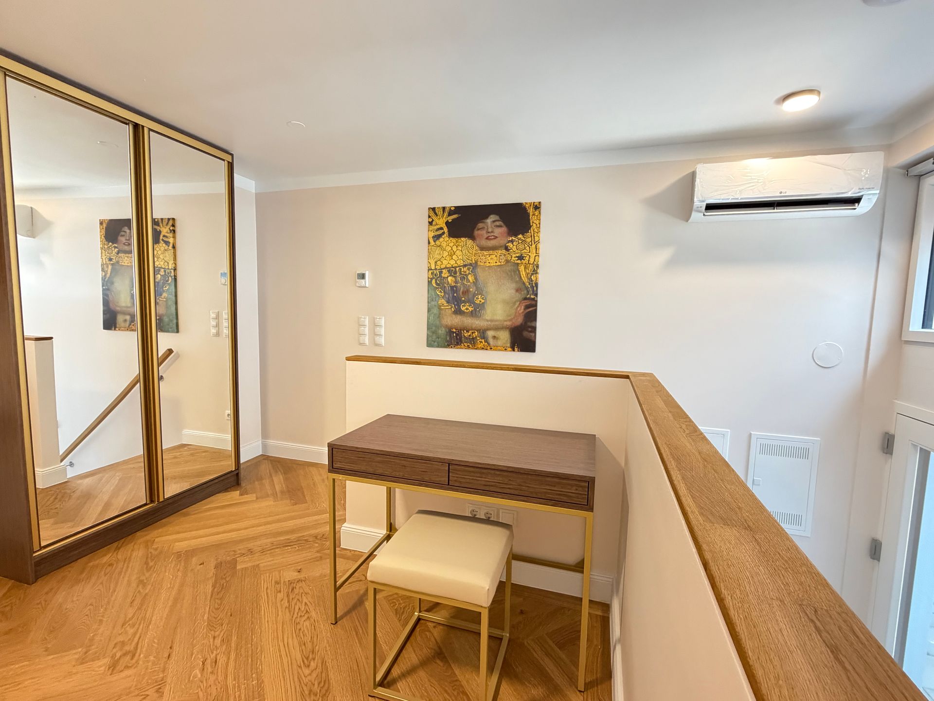 Cozy loft desk nook with mirrored wardrobe, small vanity table, wall art, and air conditioner