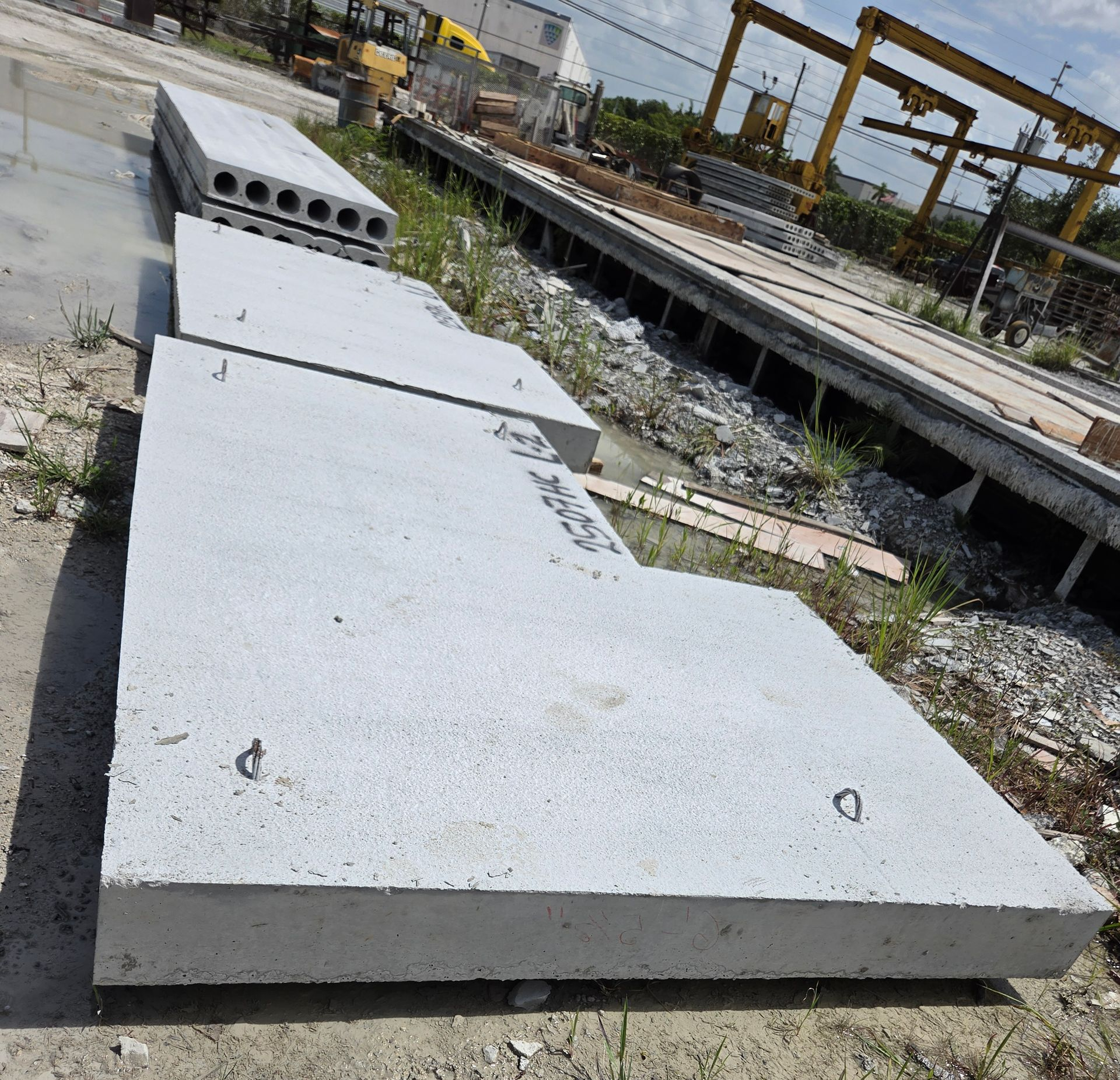 Large white concrete slab sections stacked at a construction site beside a railway track.