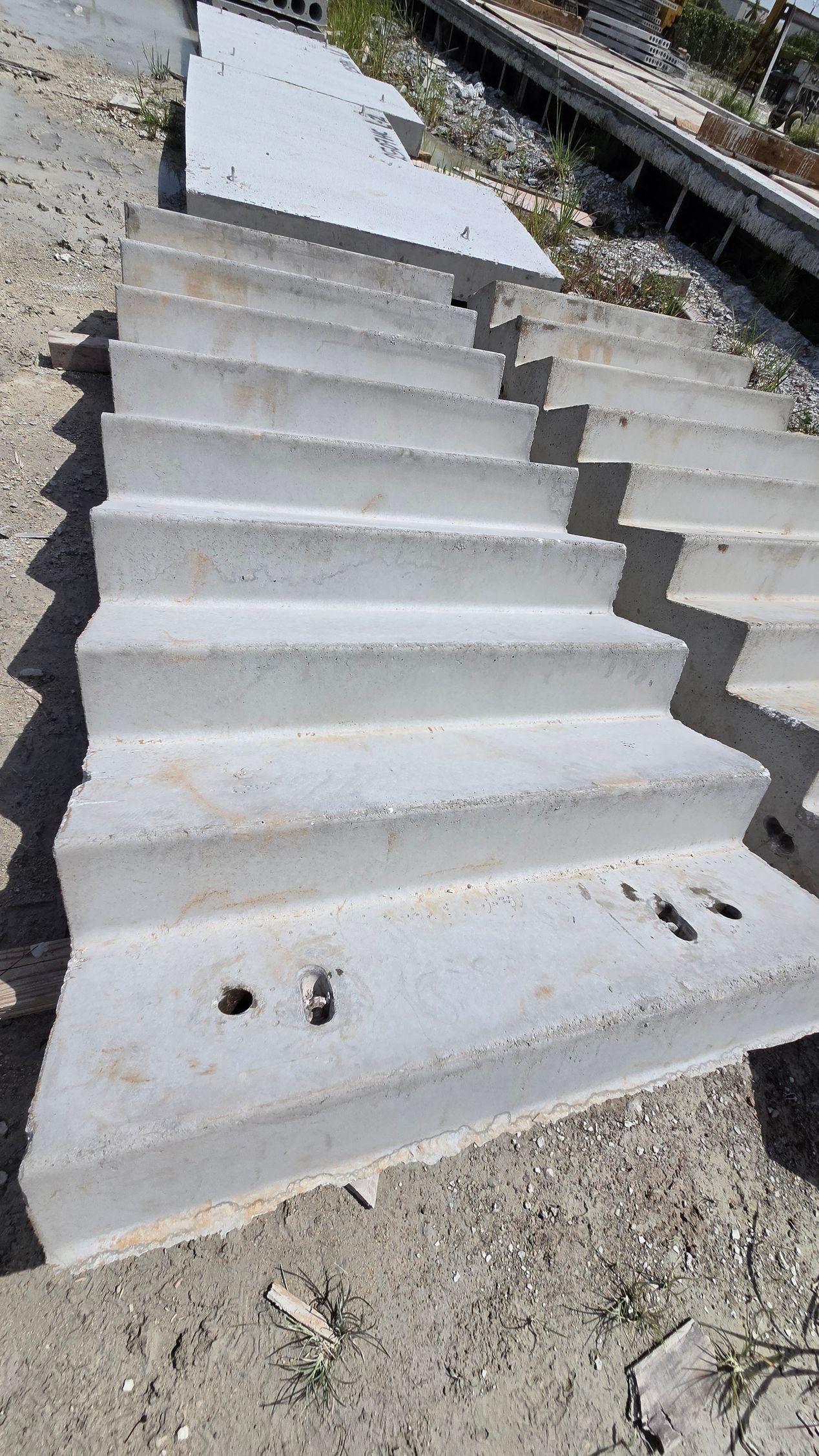 Concrete steps descending beside a gravel path, with railings and sunlight.