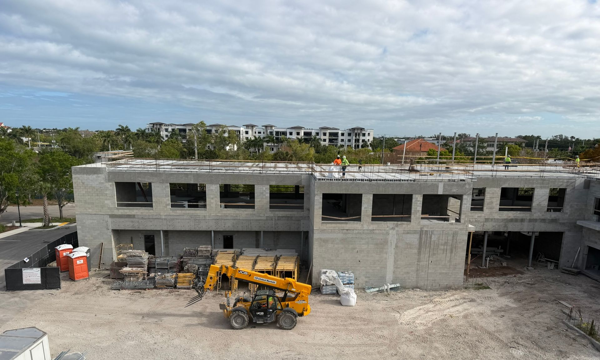 Construction site with a gray concrete building under construction and a yellow cement mixer in front