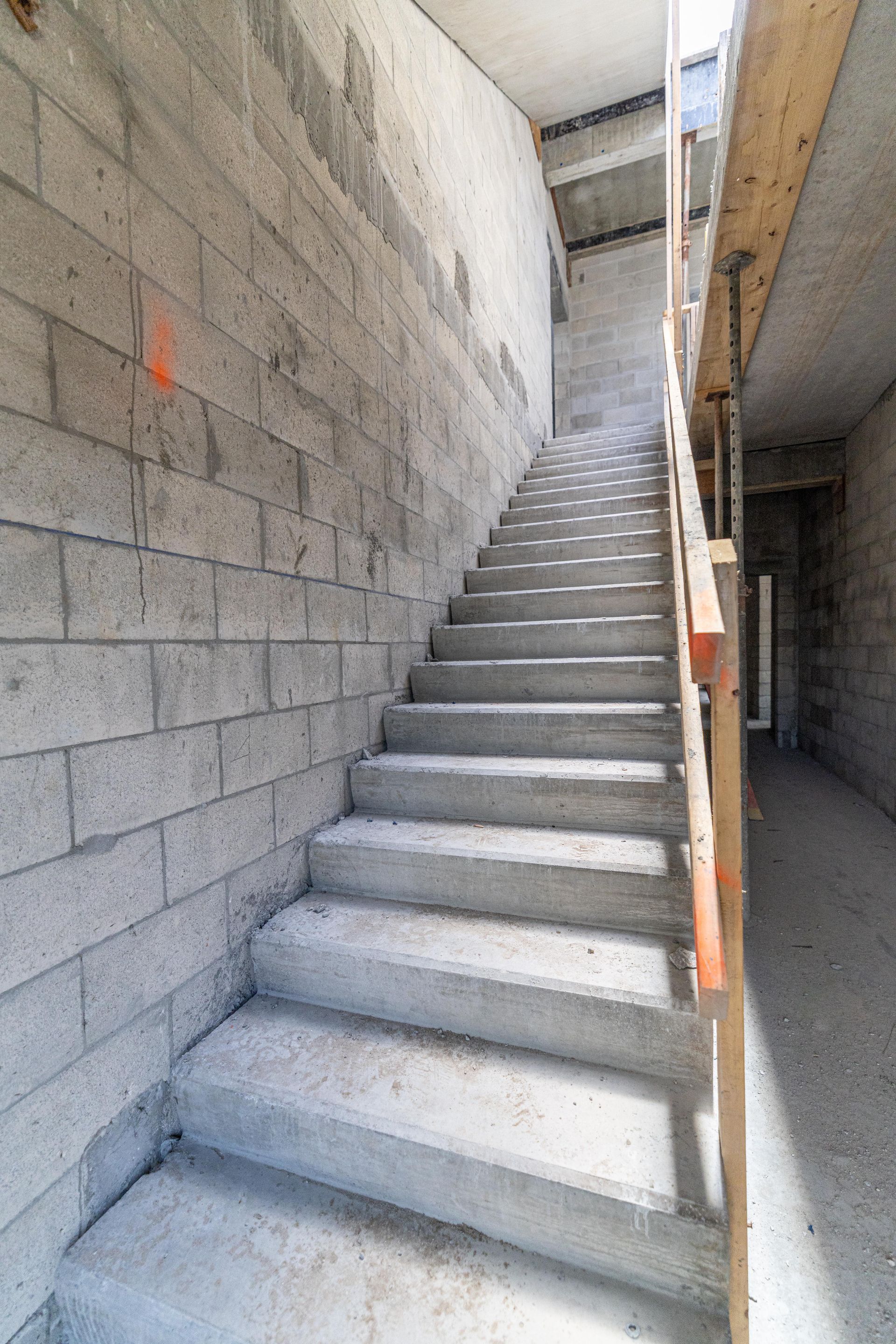Concrete stairwell between cinder block walls, unfinished indoor construction site