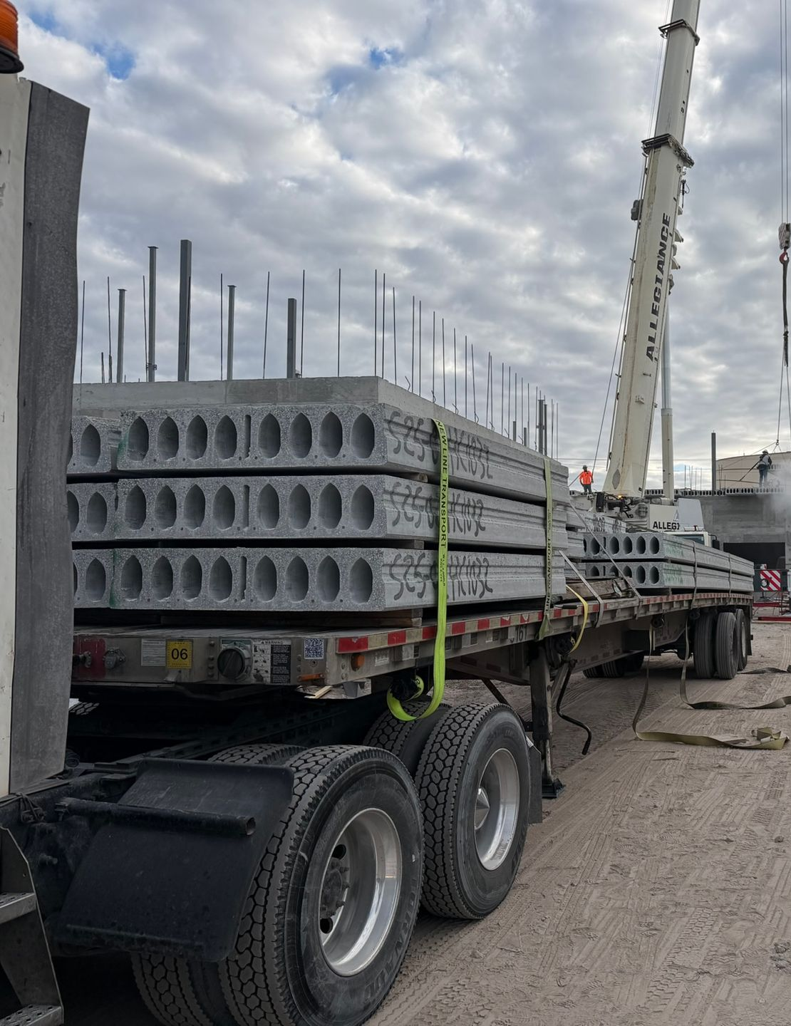 Loaded flatbed trailer carrying stacked concrete slabs with rebar at a construction site
