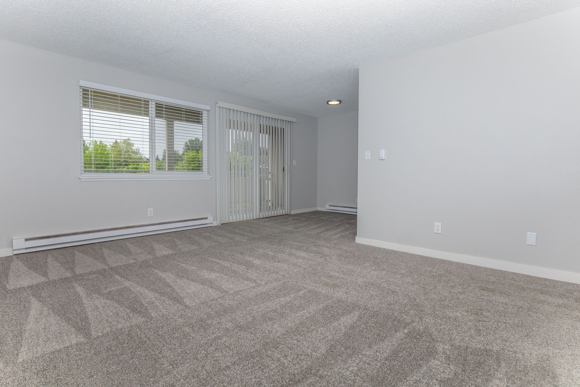 An empty living room with a sliding glass door and a balcony.