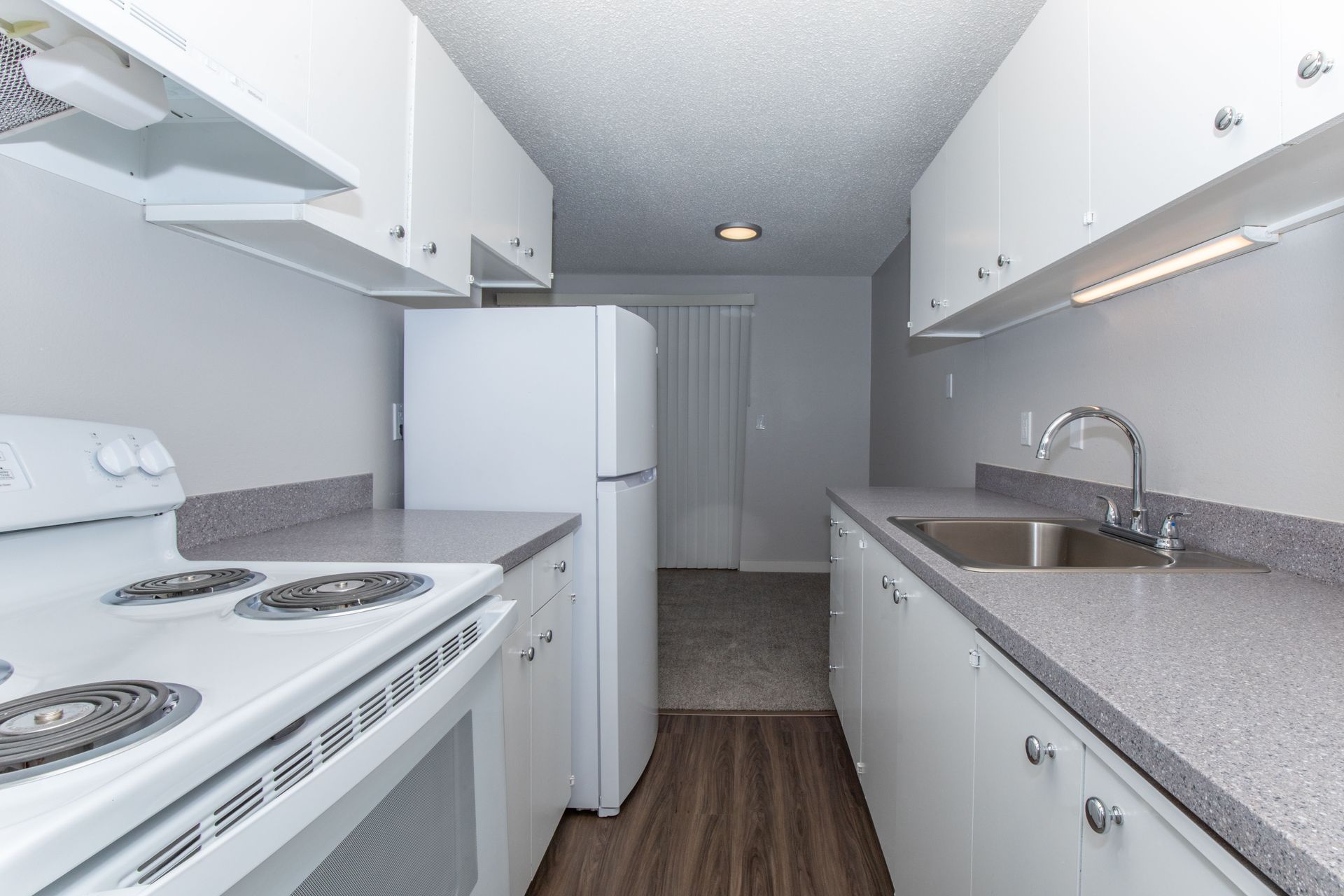 A kitchen with a stove , refrigerator , sink and cabinets.