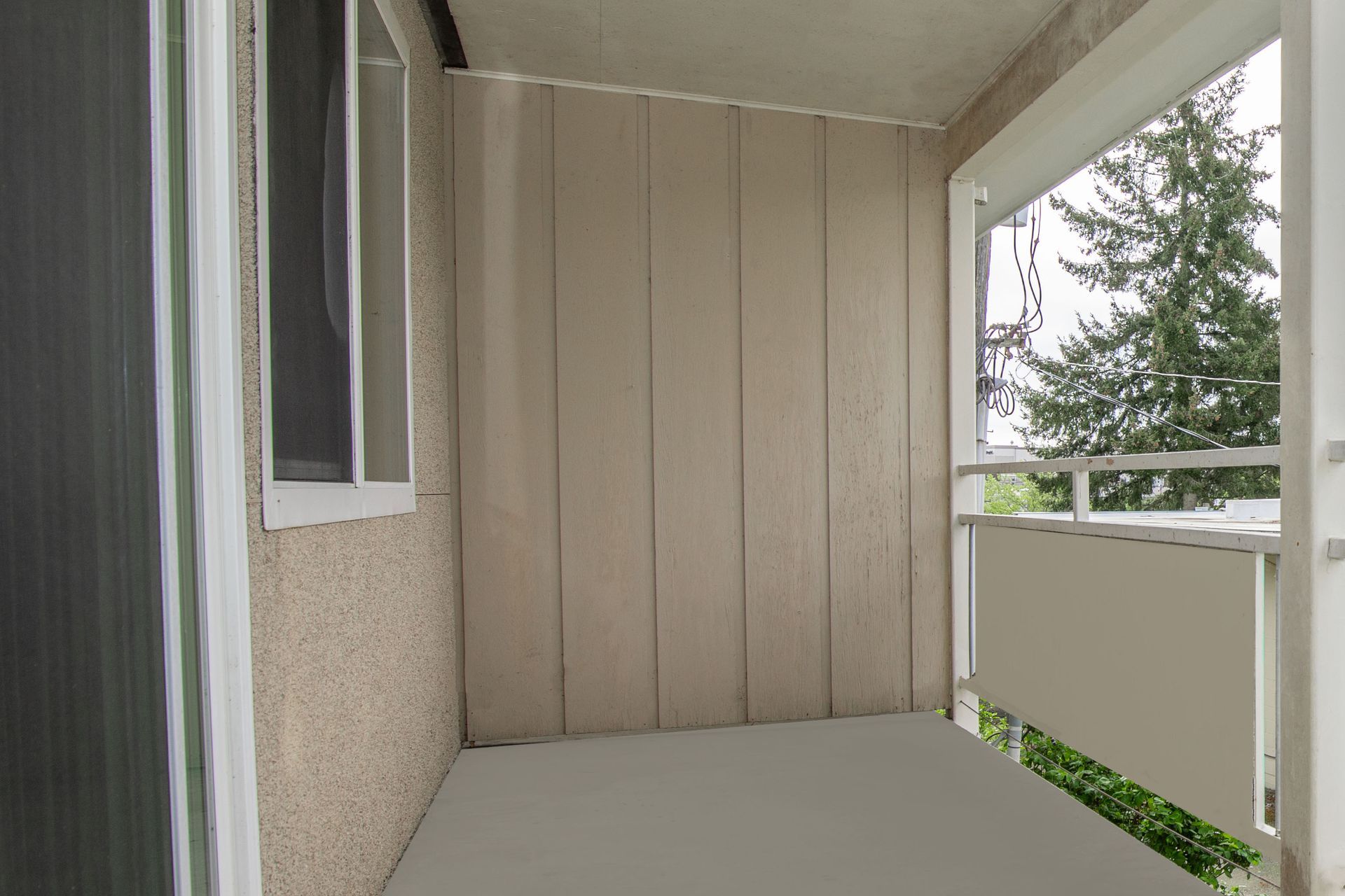 An empty balcony with a sliding glass door and a window.