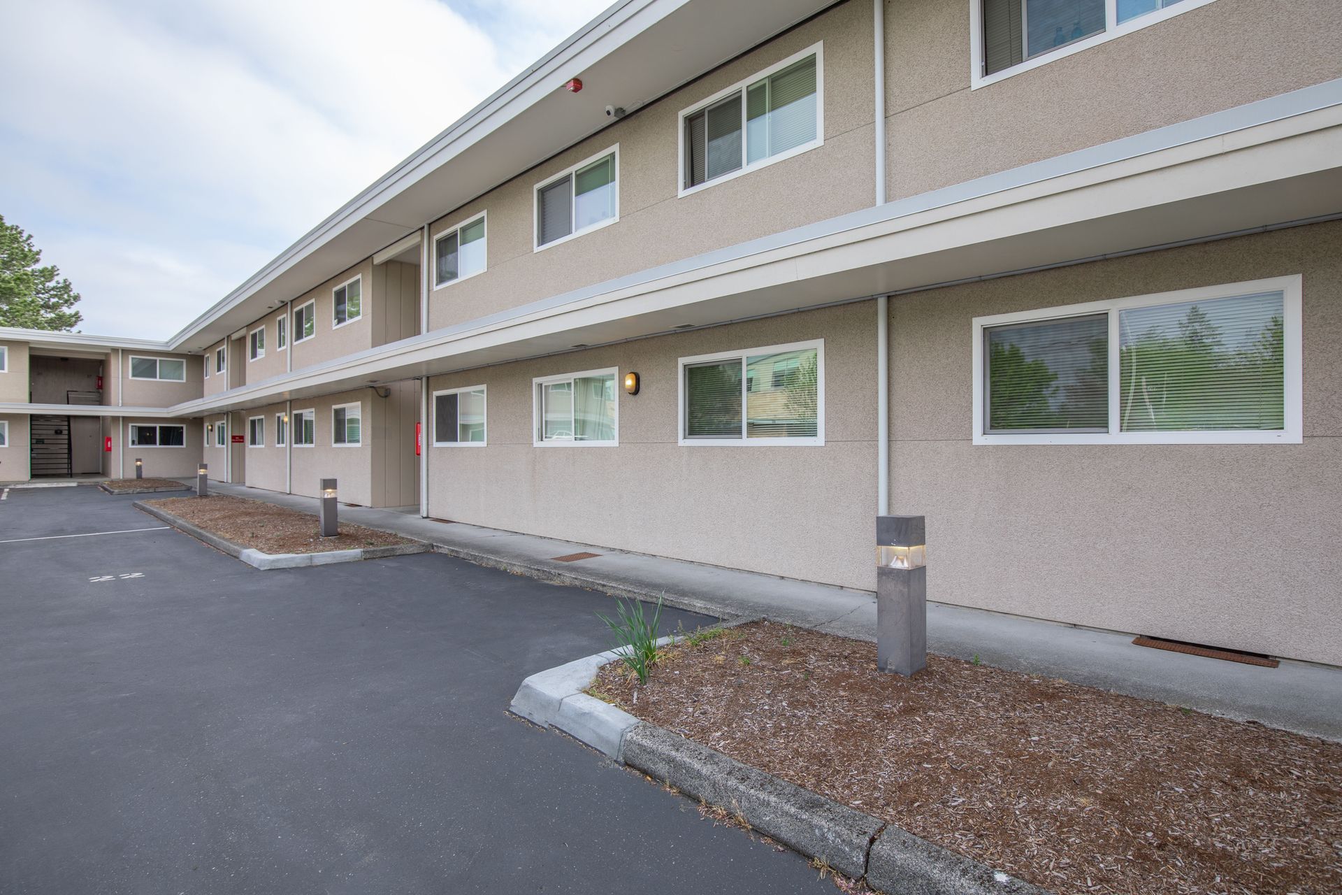 A large apartment building with a lot of windows and a parking lot in front of it.