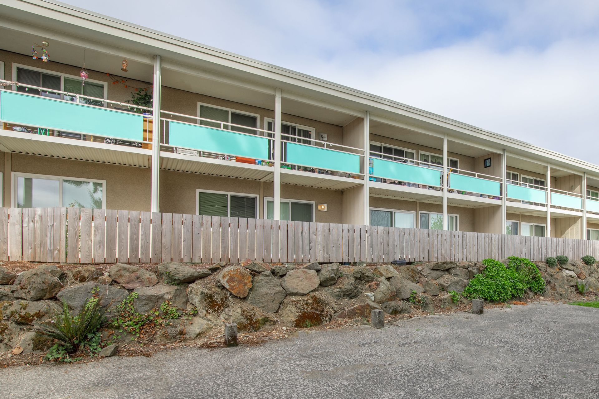A large apartment building with blue balconies and a wooden fence