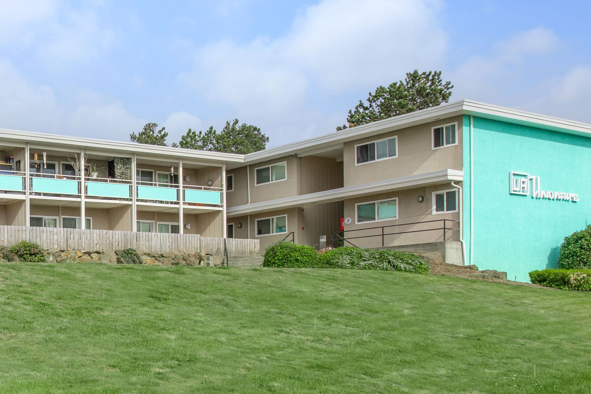 A large apartment building is sitting on top of a lush green hillside.